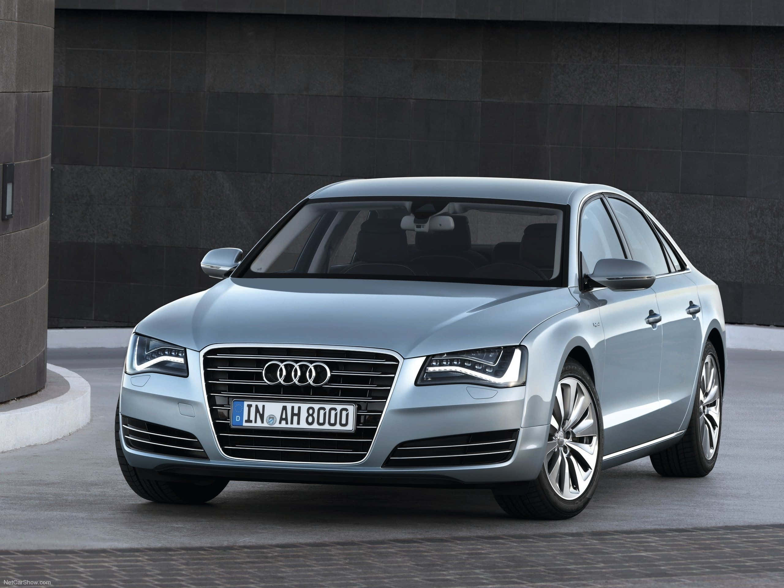 Audi S8 桌布 壁紙 — 一輛時尚的銀色奧迪A8轎車在明亮的日光下停靠在深灰色瓷磚牆邊。