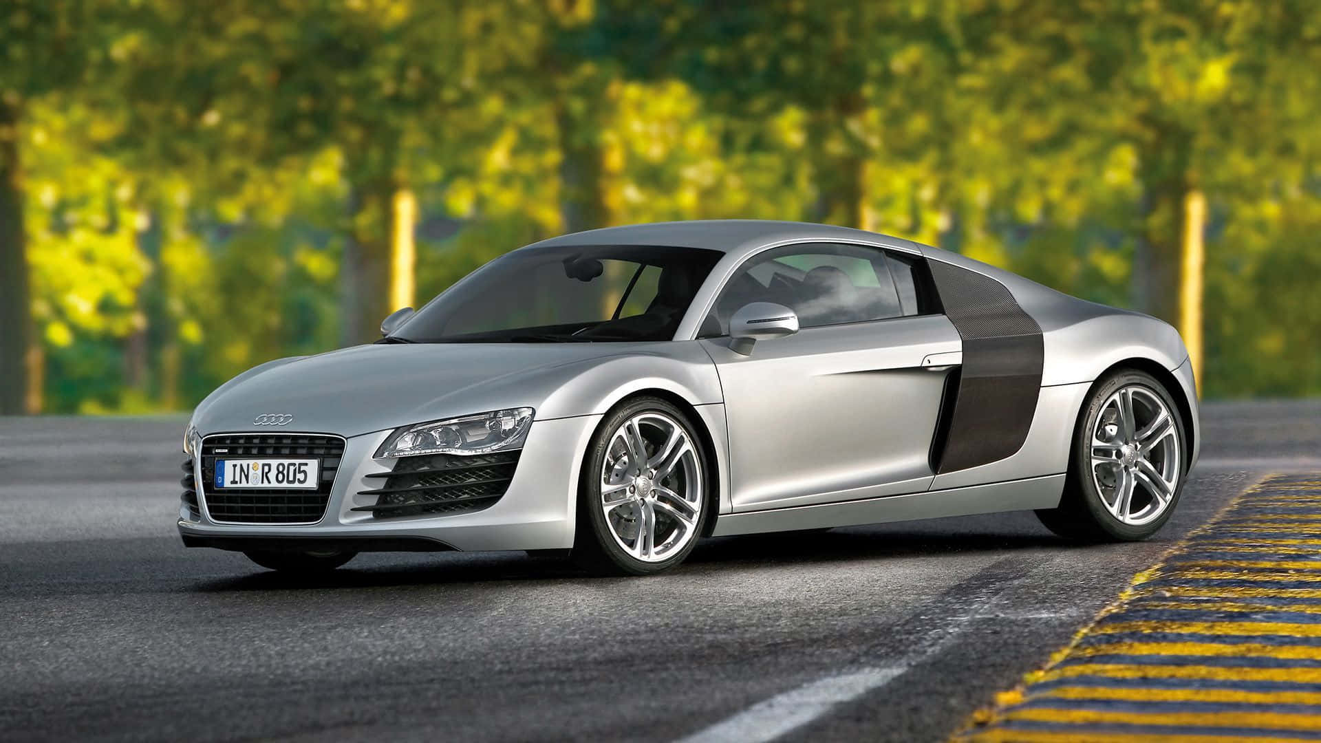 cars 桌布 壁紙 — 一輛時尚的銀色奧迪R8跑車停泊在柏油路上，背景有模糊的綠色樹木。