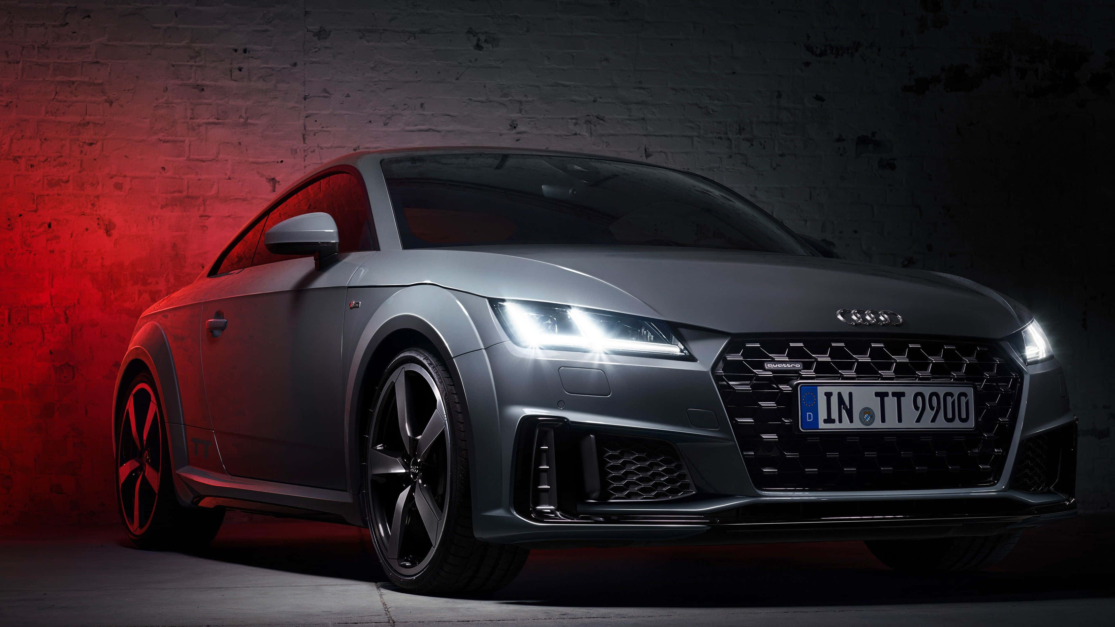 Audi Tt 桌布 壁紙 — 一輛時尚的銀色奧迪TT跑車在戲劇性的紅色燈光下，以紋理磚牆為背景閃耀著光芒。