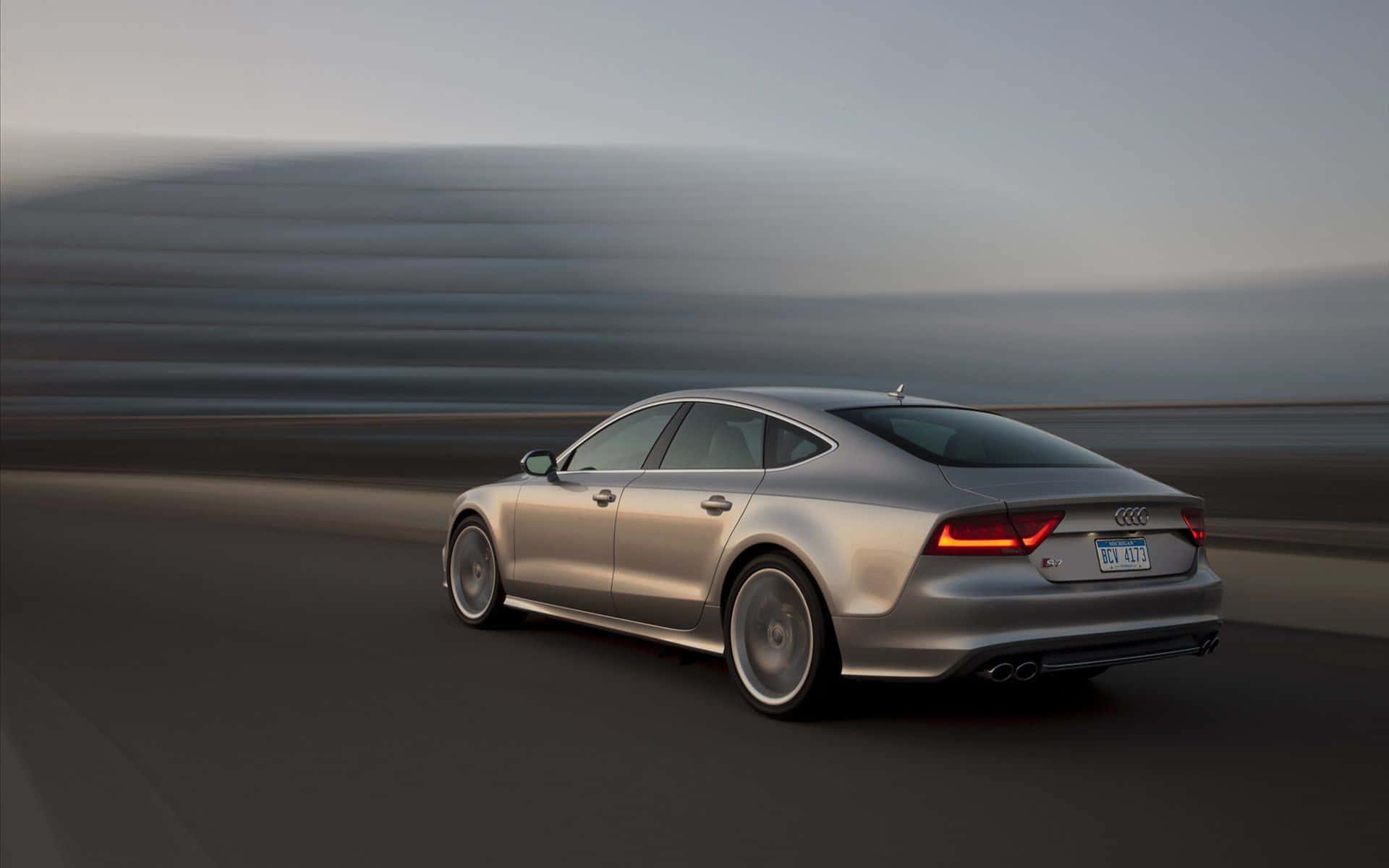 Audi S7 桌布 壁紙 — 一輛時尚的銀色奧迪轎車在道路上疾馳，背景模糊的動感傳達出高速。