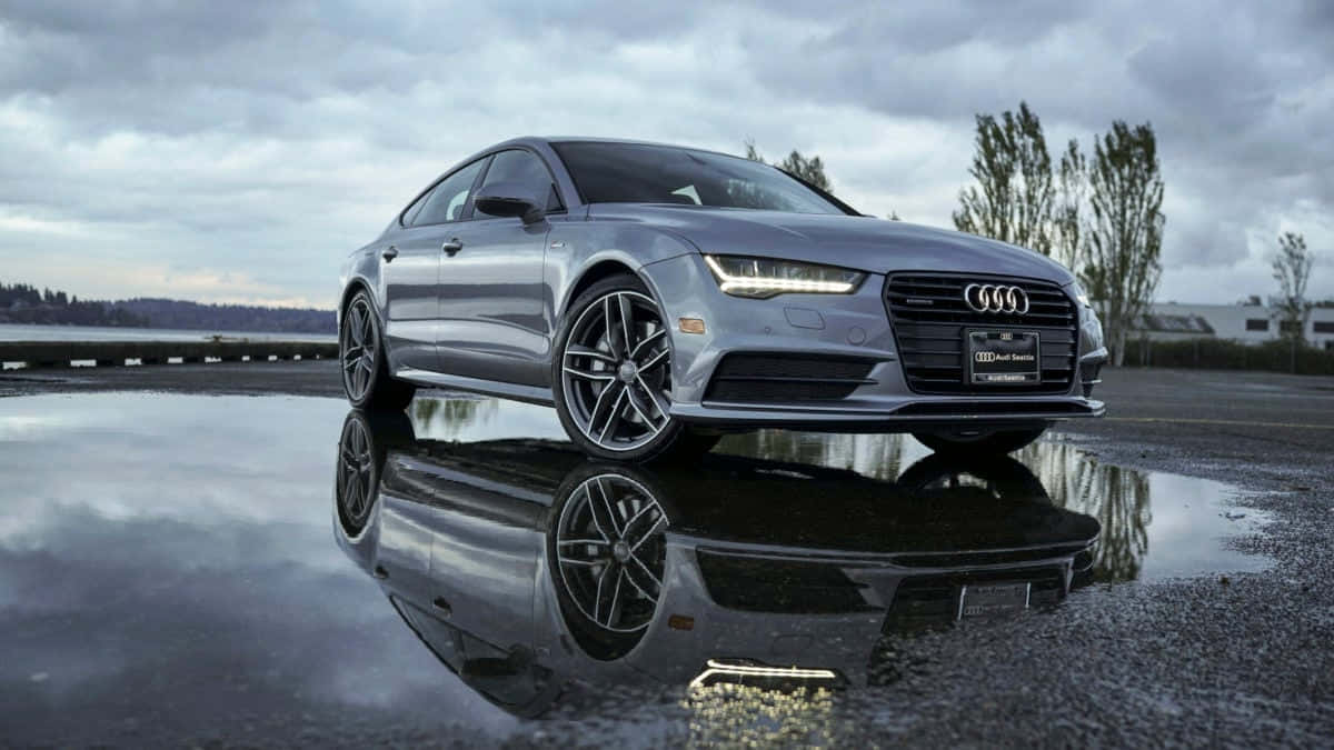 Audi S7 桌布 壁紙 — 一輛時尚的銀色奧迪轎車完美地倒映在陰天下的雨水中。