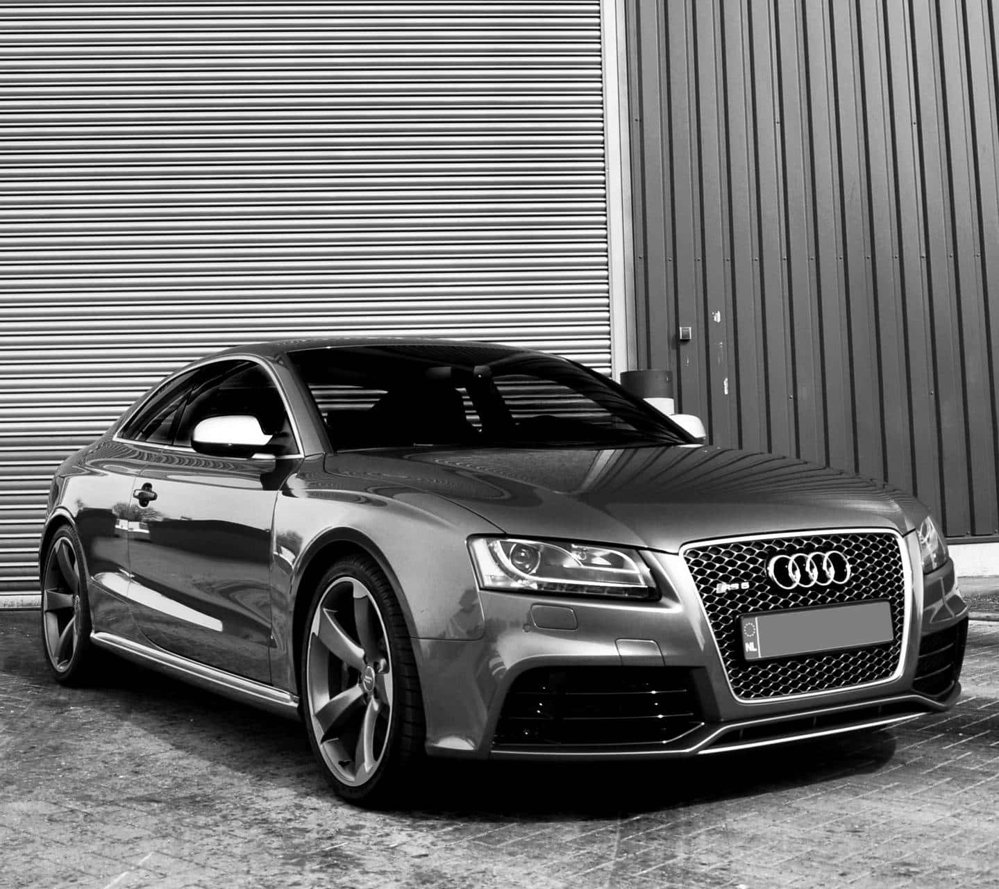 Audi S6 桌布 壁紙 — 一輛時尚的銀色奧迪運動轎跑車停在單色波紋金屬車庫門前。
