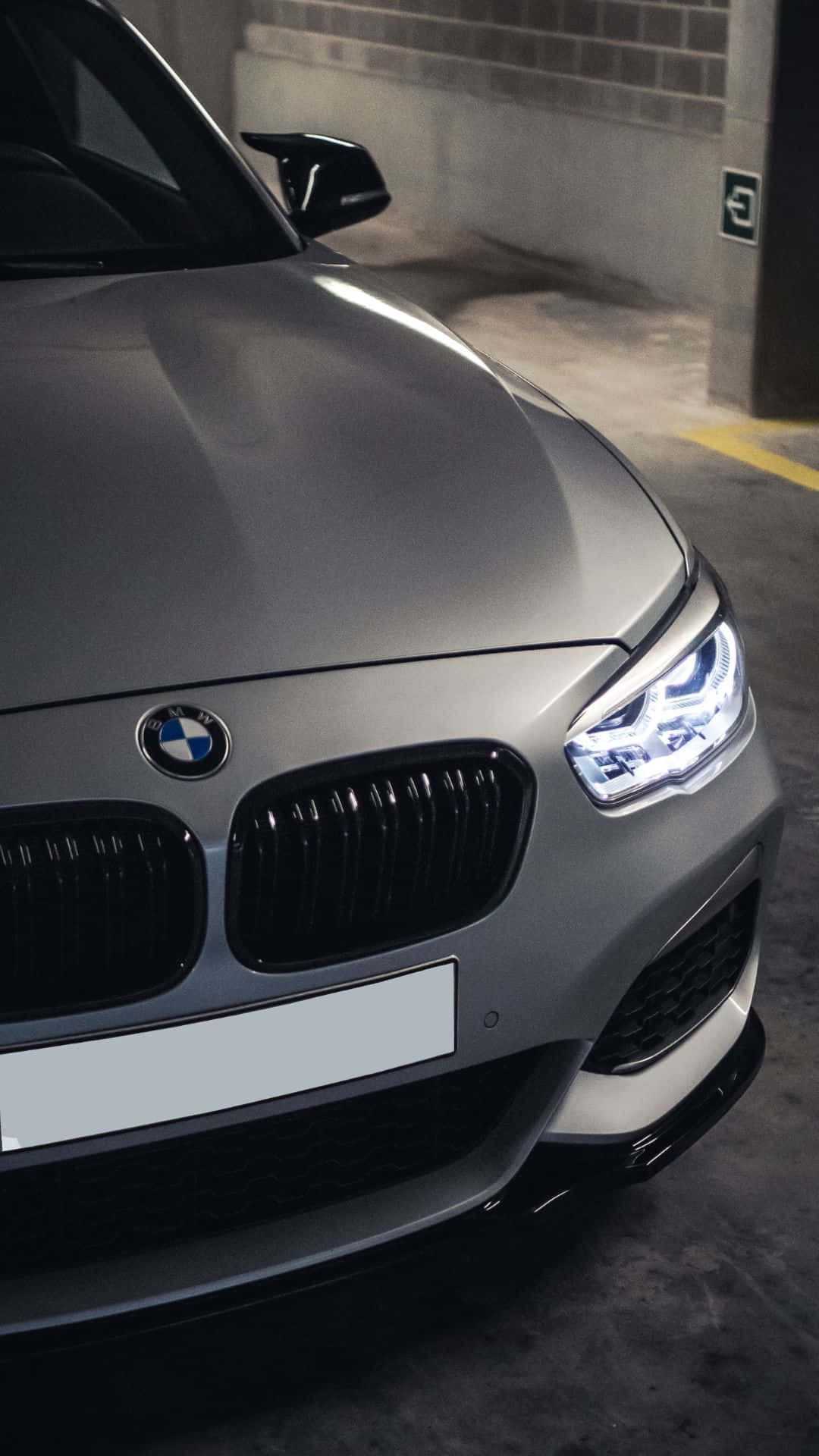 Android Bmw 桌布 壁紙 — 一輛時尚的銀色寶馬跑車，車頭燈閃爍，停放在光線昏暗的地下停車場。
