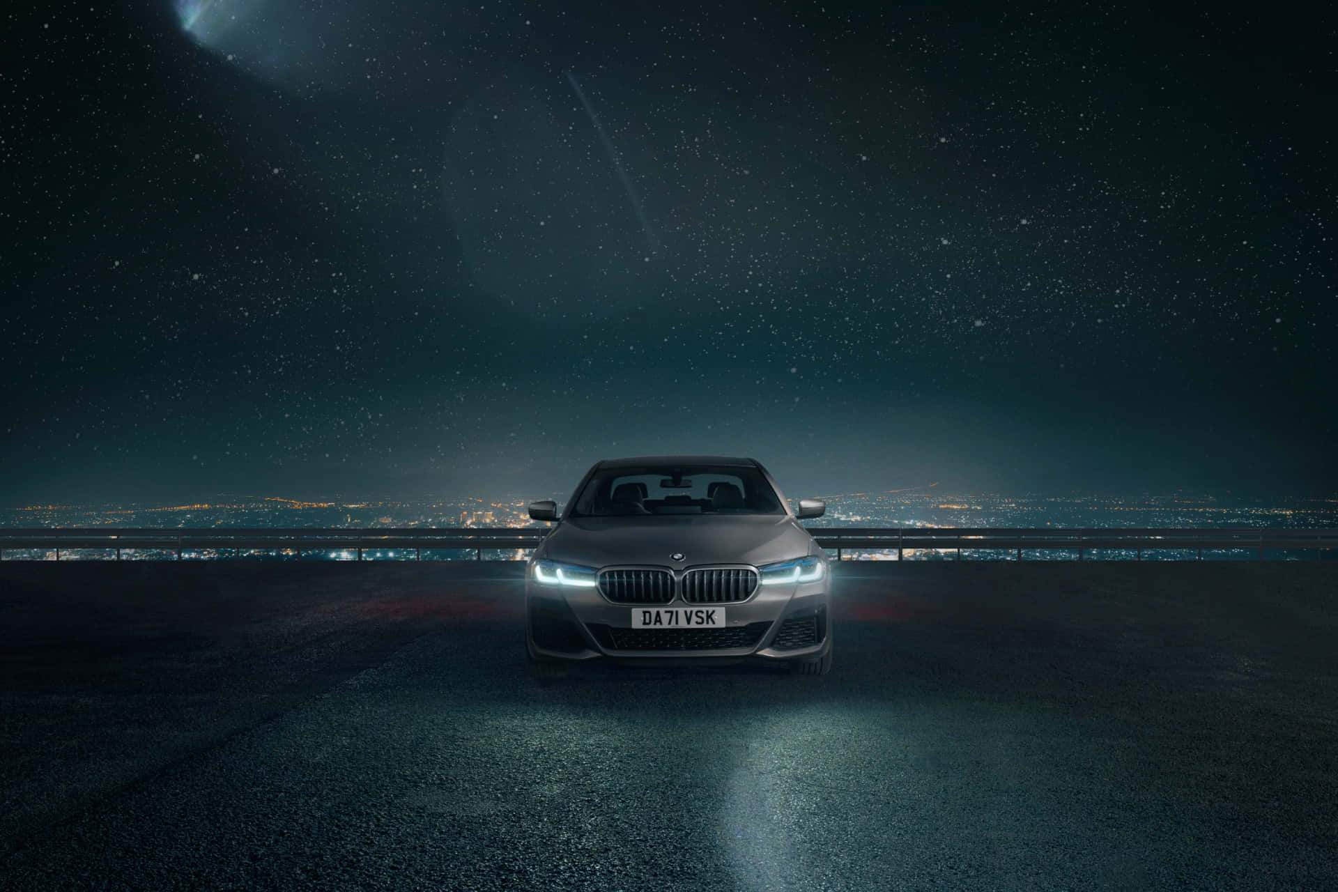 BMW 動圖 桌布 壁紙 — 一輛時尚的銀色寶馬轎車在繁星點點的夜空下閃耀，下方黑暗的高速公路上城市燈光閃爍。