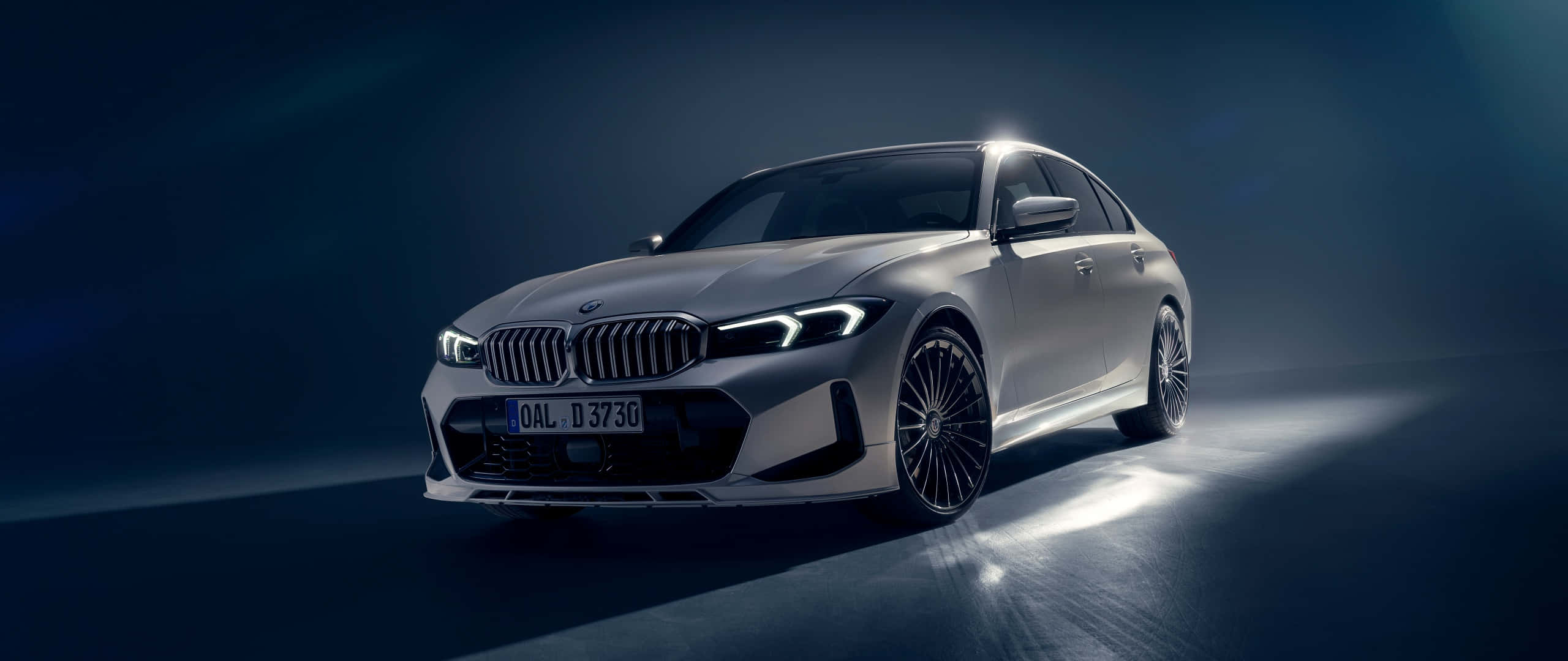 Bmw 328 桌布 壁紙 — 一輛時尚的銀色寶馬轎車在黑暗的攝影棚背景下，在反射地板上閃耀著戲劇性的聚光燈。