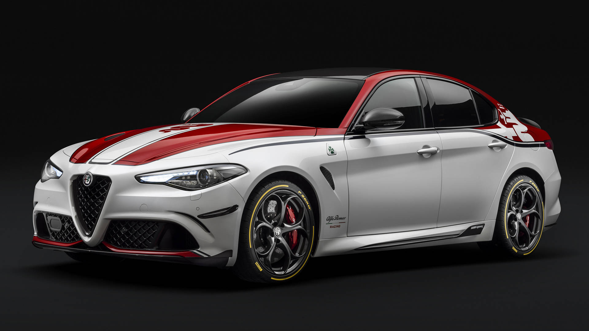 alfa romeo iPhone 桌布 壁紙 — 一輛時尚的銀色愛快羅密歐轎車，帶有醒目的紅色賽車條紋和黑色飾邊，在深色工作室背景下蓄勢待發。