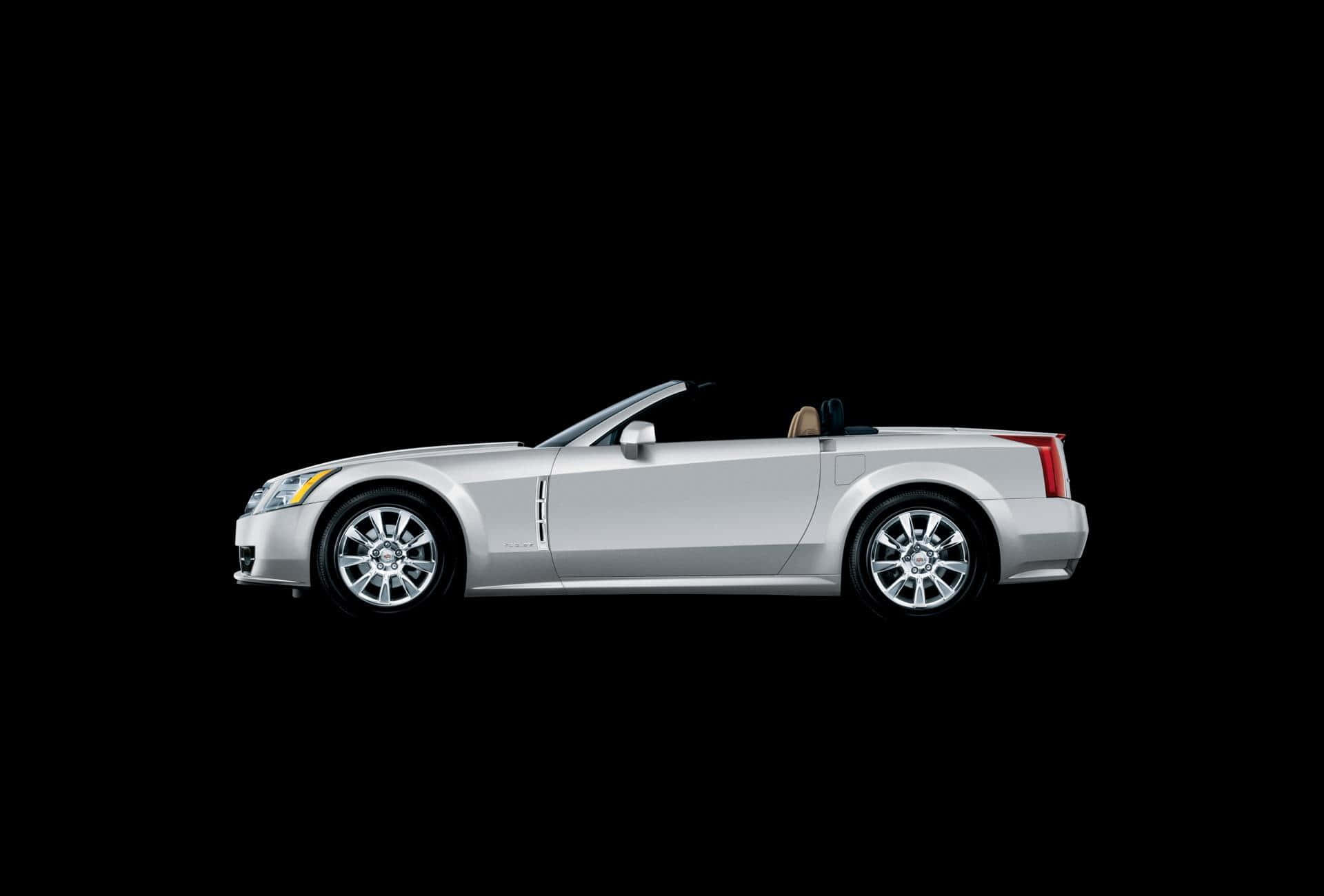 Cadillac Xlr 桌布 壁紙 — 一輛時尚的銀色敞篷跑車在純黑色背景上以側面輪廓展示。