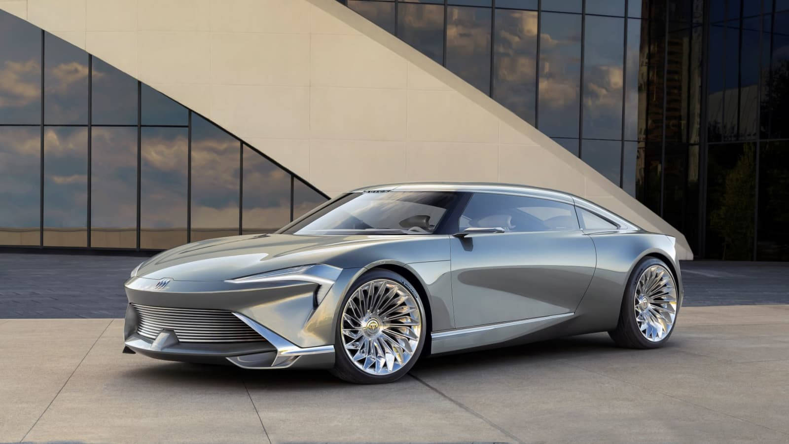 Buick 桌布 壁紙 — 一輛時尚的銀色未來主義跑車，配備精緻的輪圈，停在一棟現代玻璃和混凝土建築前。