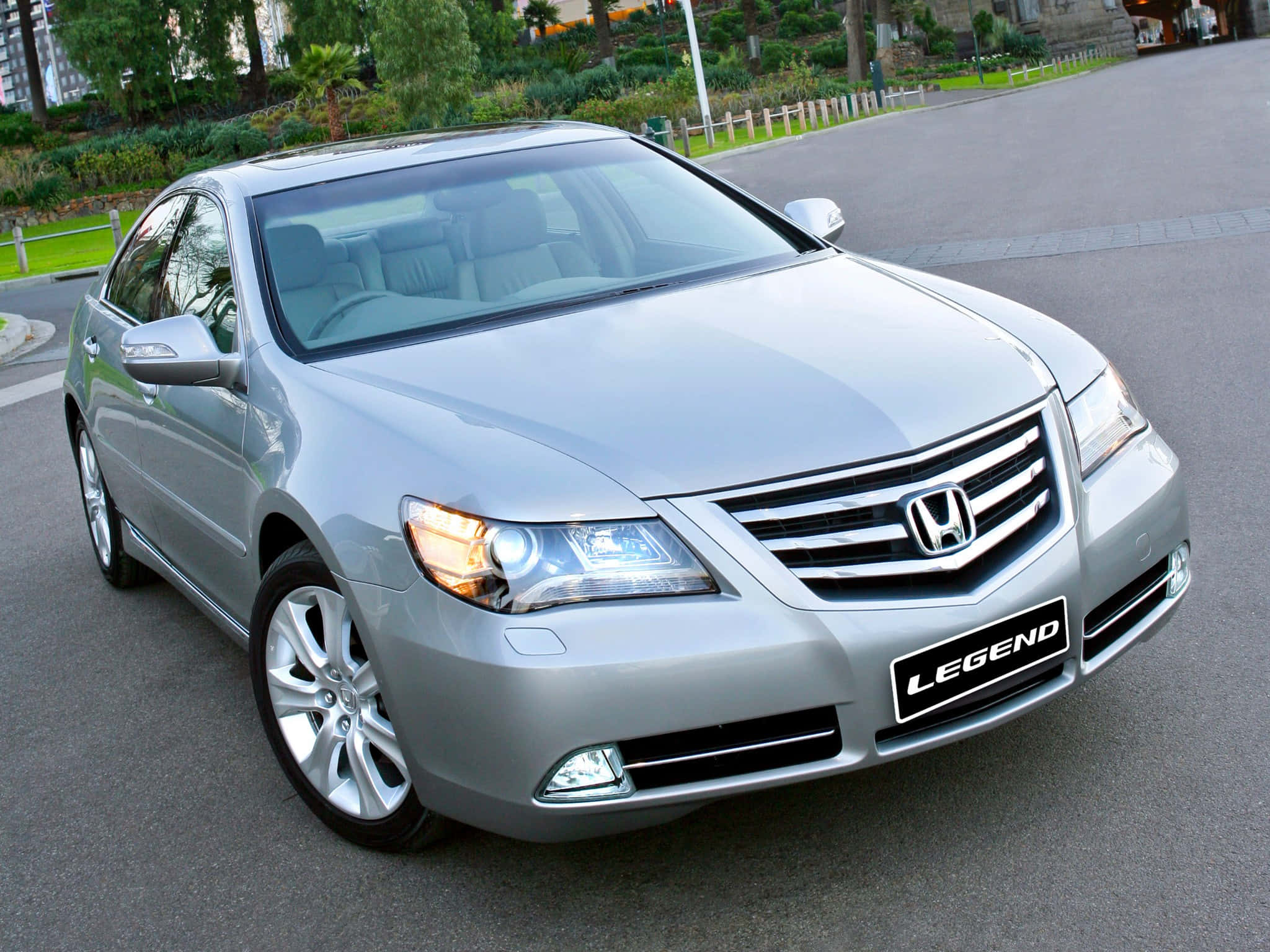 Honda Legend 桌布 壁紙 — 一輛時尚的銀色本田Legend轎車停在鋪砌的道路上，背景有綠化和建築物。