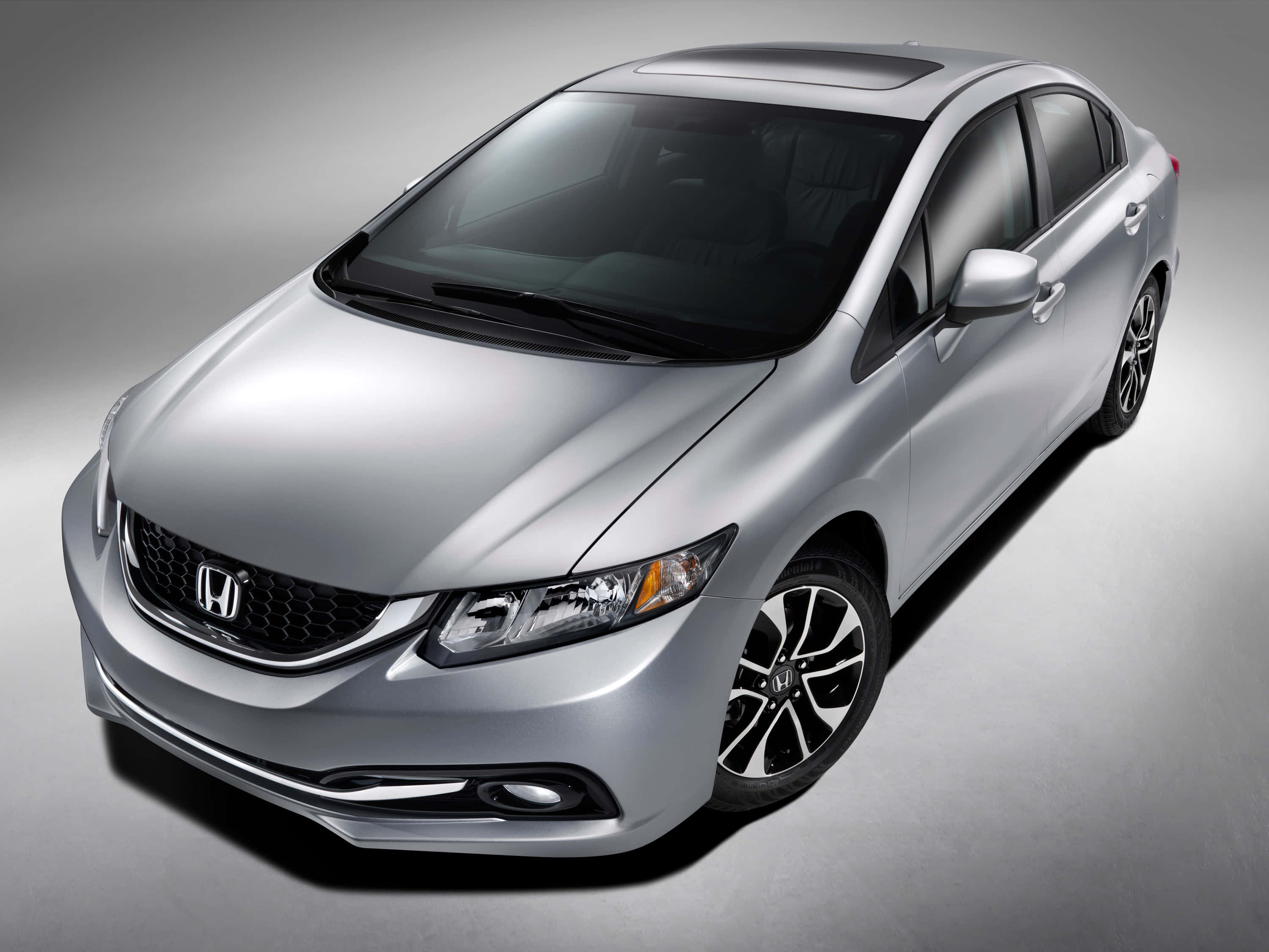 Honda Civic 桌布 壁紙 — 一輛時尚的銀色本田房車在攝影棚燈光下閃耀，高角度視角展現其現代設計和合金輪圈。