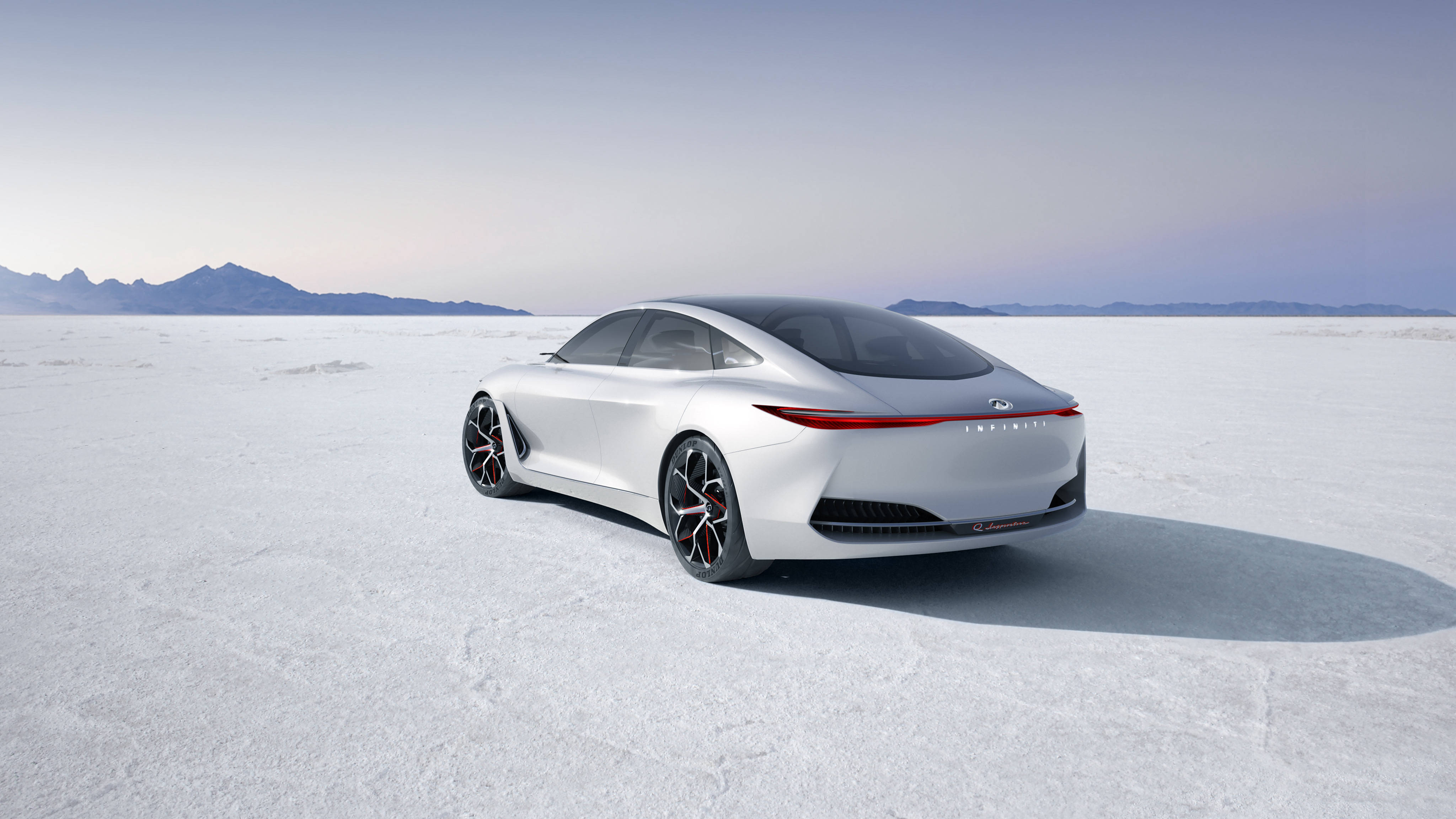 Infiniti 桌布 壁紙 — 一輛時尚的銀色概念車，帶有紅色裝飾輪，停放在廣闊的白色鹽灘上，天空蒼白，遠處有山脈。