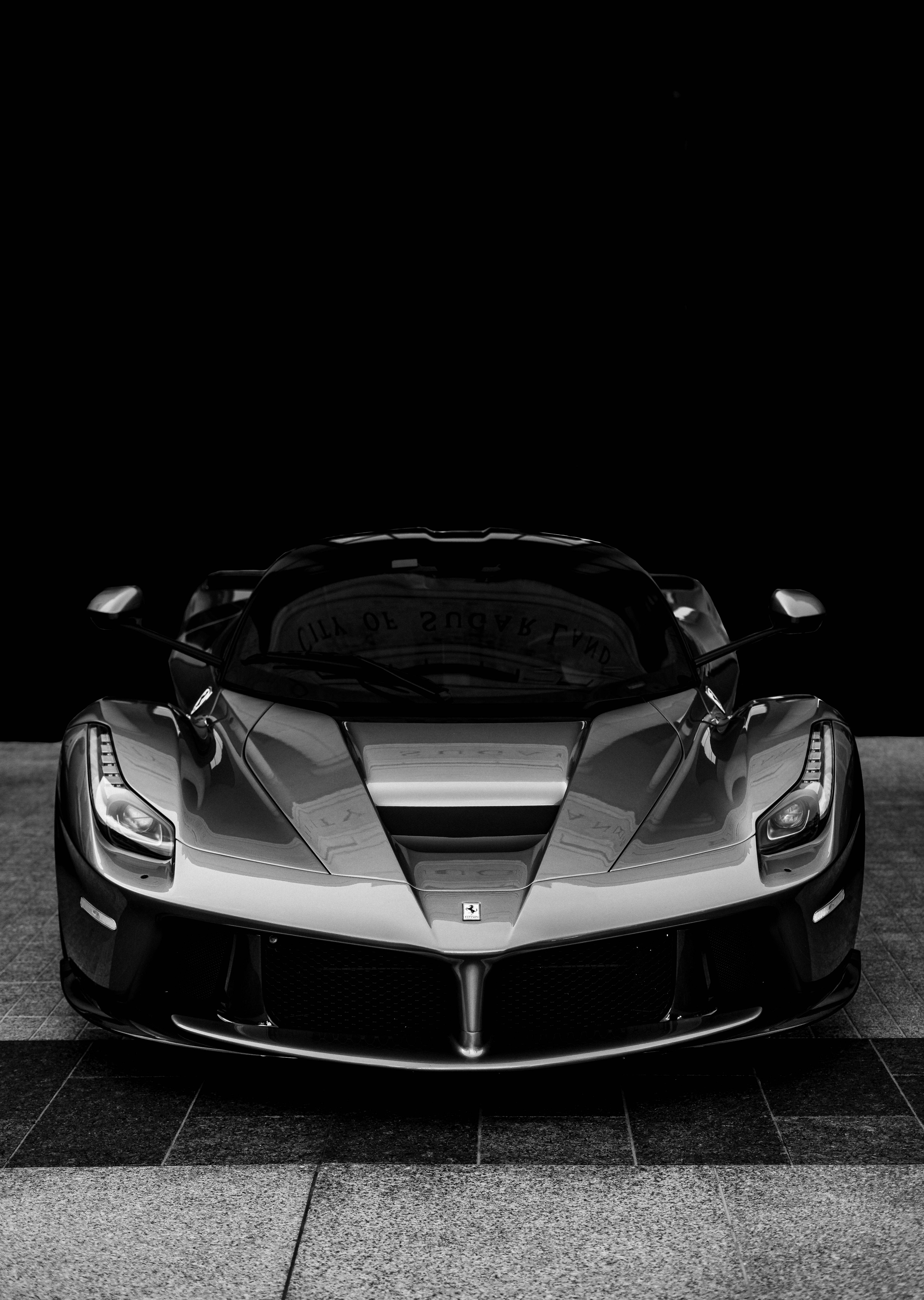跑車 桌布 壁紙 — 一輛時尚的銀色法拉利 LaFerrari 在瓷磚地板上正面朝向樸素的黑色背景。
