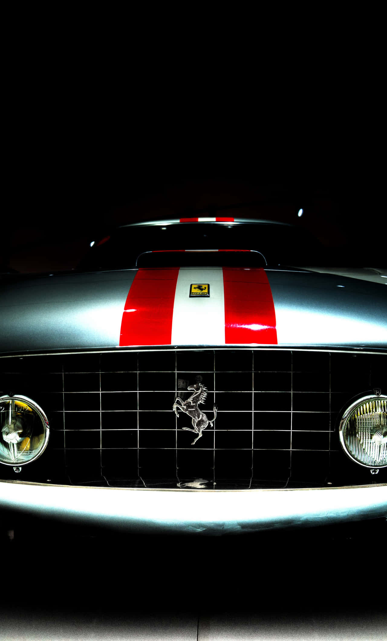 Car Front View 桌布 壁紙 — 一輛時尚的銀色法拉利，帶有紅色和白色賽車條紋，在黑色背景的戲劇性聚光燈下閃耀。