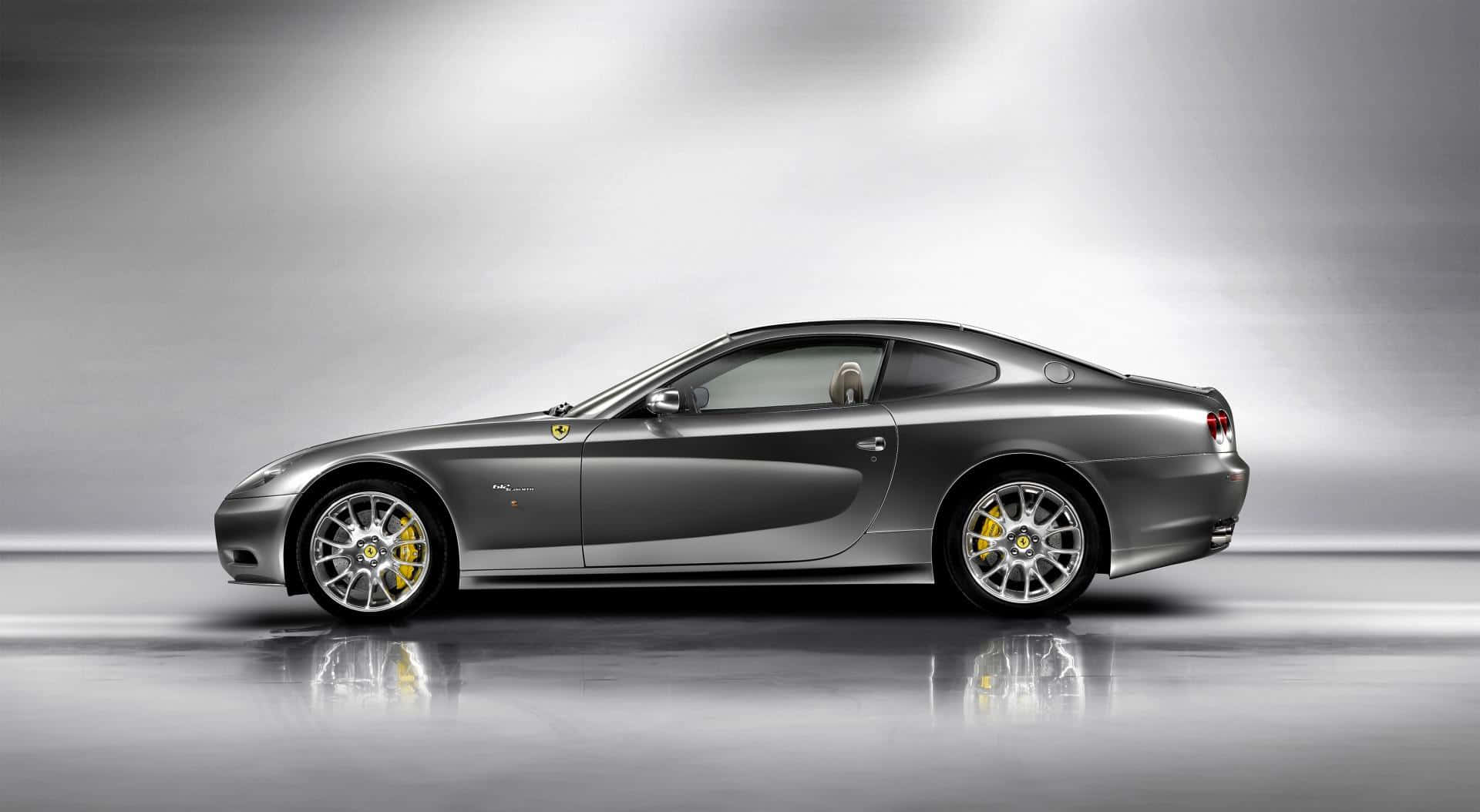 Ferrari 612 Scaglietti 桌布 壁紙 — 一輛時尚的銀色法拉利612 Superamerica轎跑車在攝影棚燈光下閃閃發光，配備黃色制動卡鉗和反光地板。
