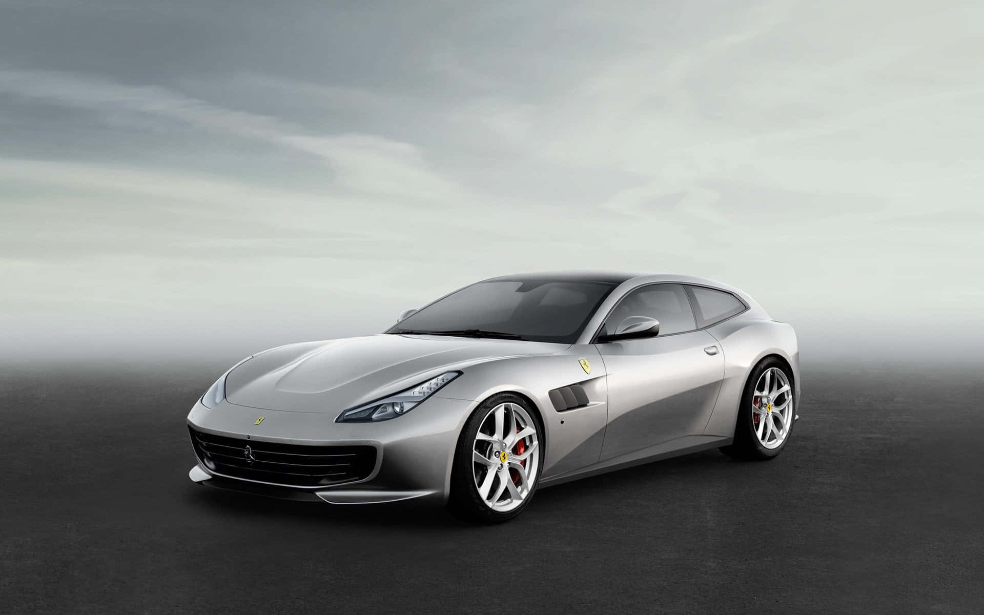 Ferrari Gtc4lusso 桌布 壁紙 — 一輛時尚的銀色法拉利跑車配備紅色制動卡鉗，在暗淡灰色天空下停放在深色表面上。