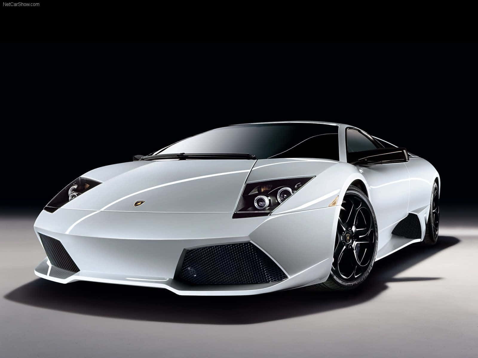 Top 10 Car 桌布 壁紙 — 一輛時尚的銀色藍寶堅尼跑車，帶有黑色飾邊和銳利的棱角設計，在黑暗的攝影棚背景下被照亮。