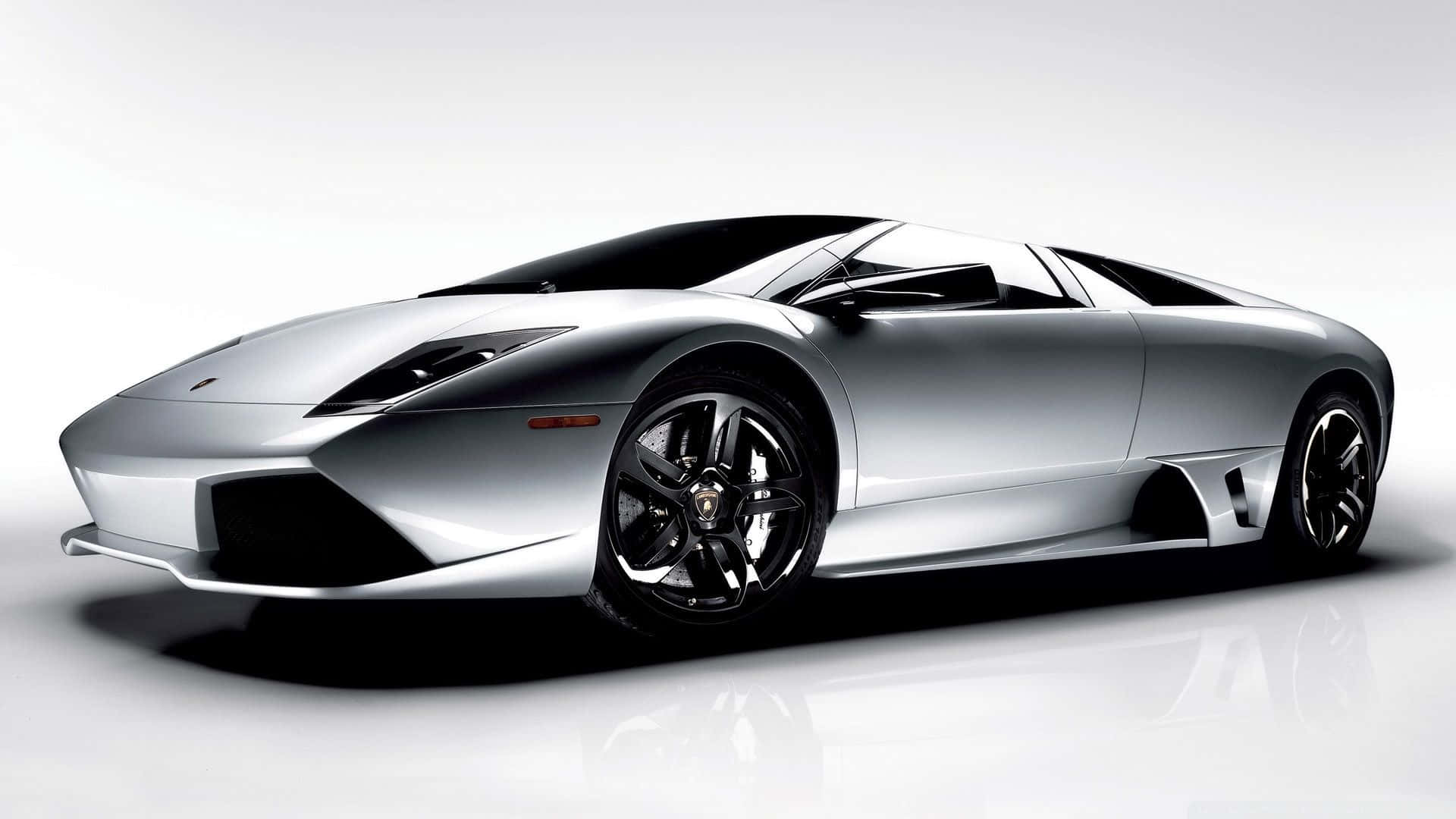 Lamborghini Murciélago 桌布 壁紙 — 一輛時尚的銀色藍寶堅尼跑車，帶有黑色飾邊和光澤表面，立於反射性白色攝影棚地板上。
