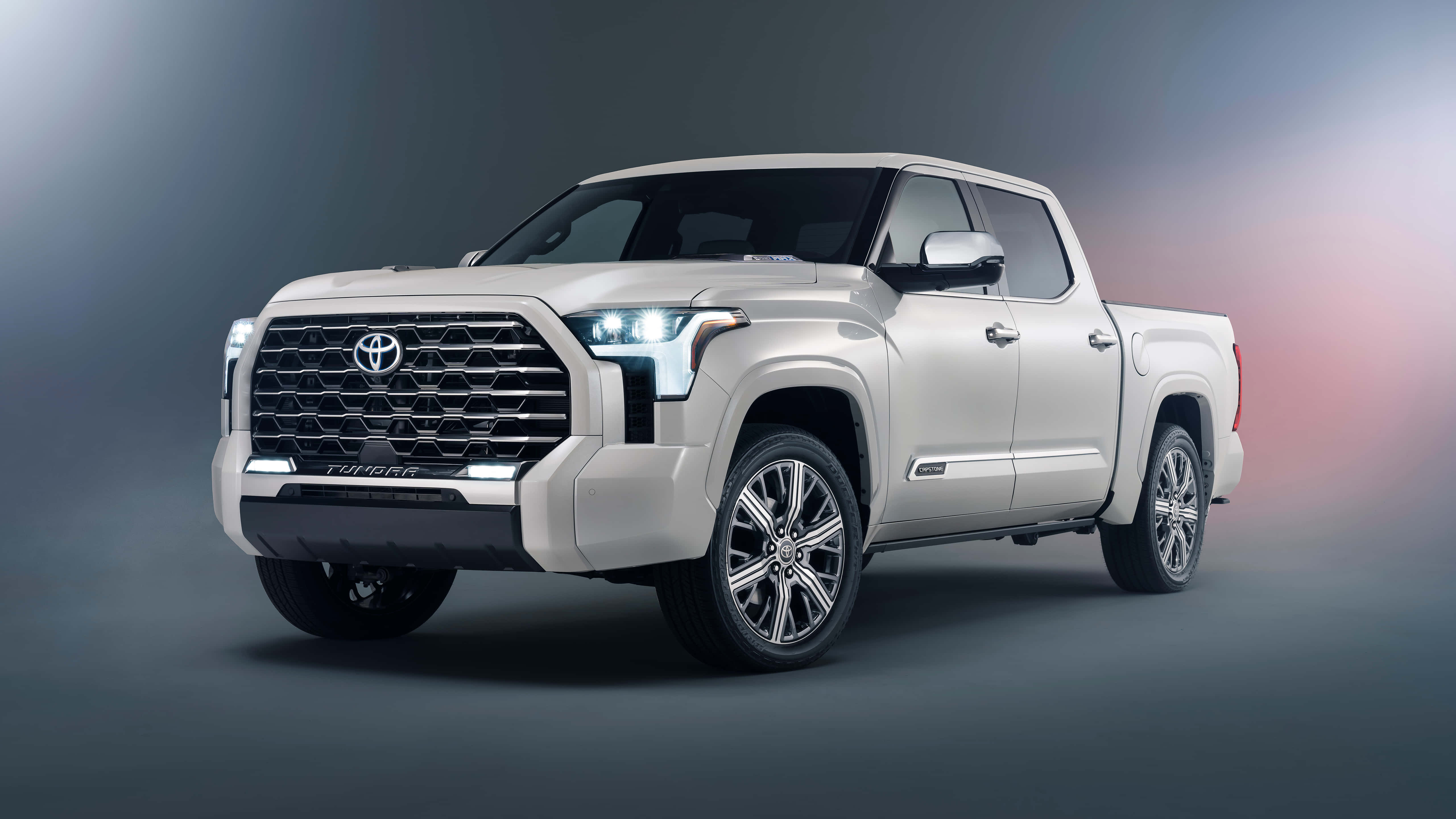 Toyota 桌布 壁紙 — 一輛時尚的銀色豐田Tundra pickup truck在攝影棚中展示，配以戲劇性燈光和灰色到粉紅色的漸變背景。