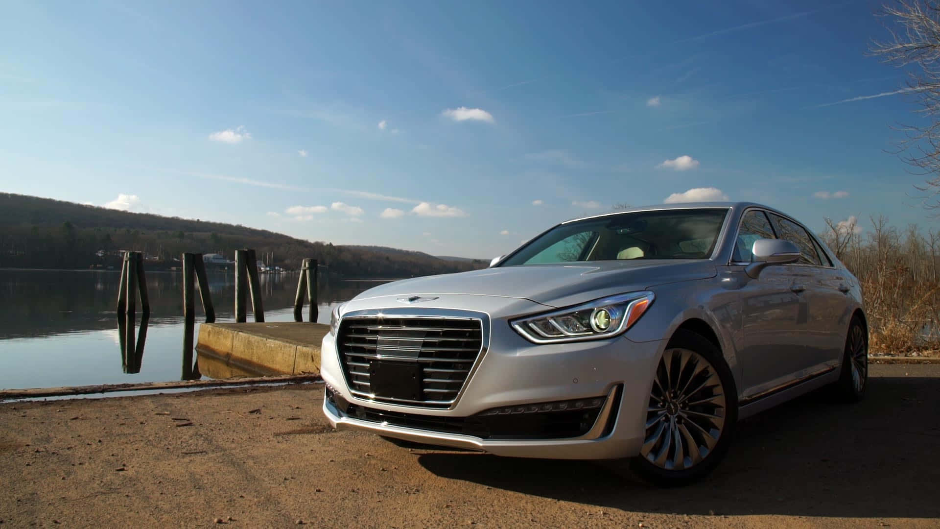 Genesis G90 桌布 壁紙 — 一輛時尚的銀色豪華轎車停泊在平靜的湖邊，天空湛藍，白雲點綴。