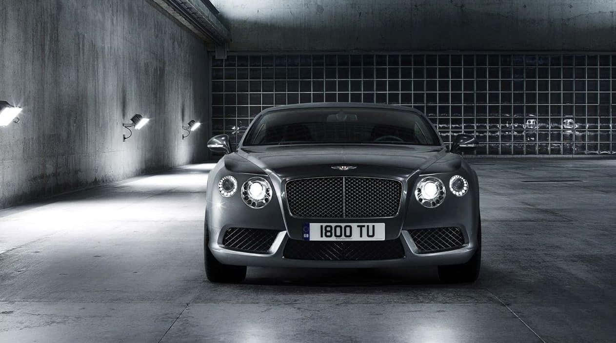 Convertible 桌布 壁紙 — 一輛時尚的銀色賓利 Continental GT 在極簡混凝土車庫的網格牆下，於聚光燈下閃閃發光。