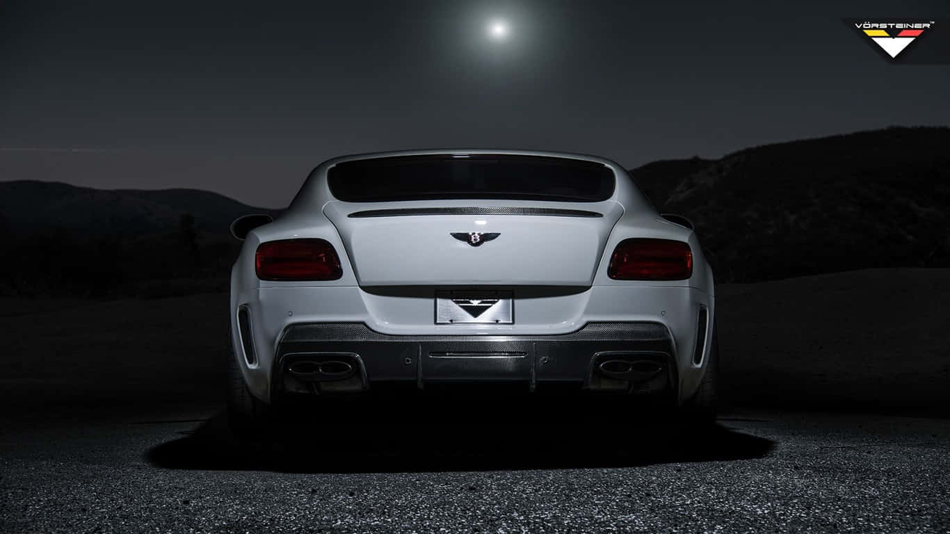 1366x768 Bentley 桌布 壁紙 — 一輛時尚的銀色賓利 Continental GT 在夜晚停泊於明亮的月光下，背景是黑暗的山丘。