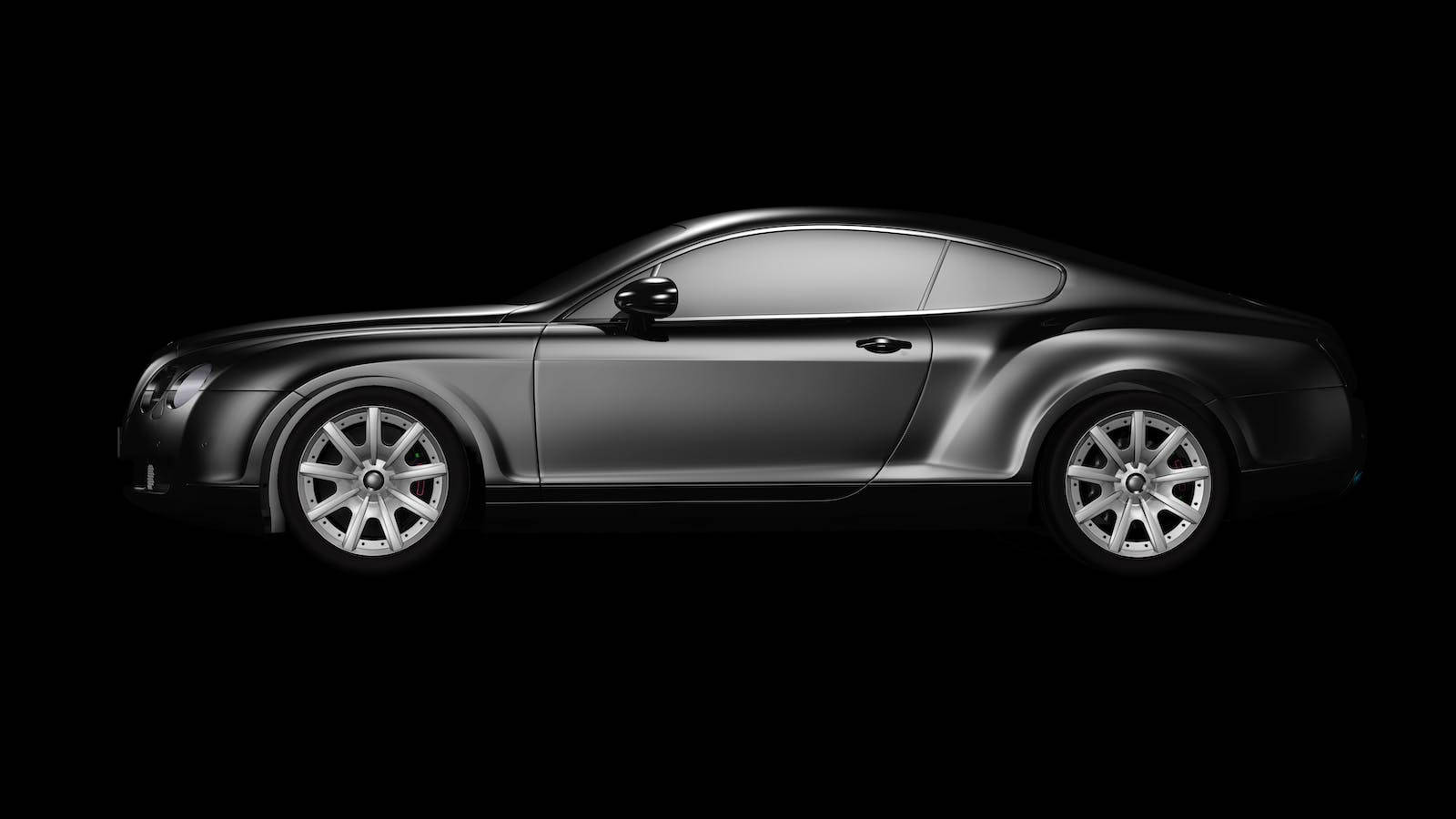 bentley HD 桌布 壁紙 — 一輛時尚的銀色賓利 Continental GT 雙門轎跑車，在純黑色背景上以側面輪廓呈現，搭配戲劇性燈光。