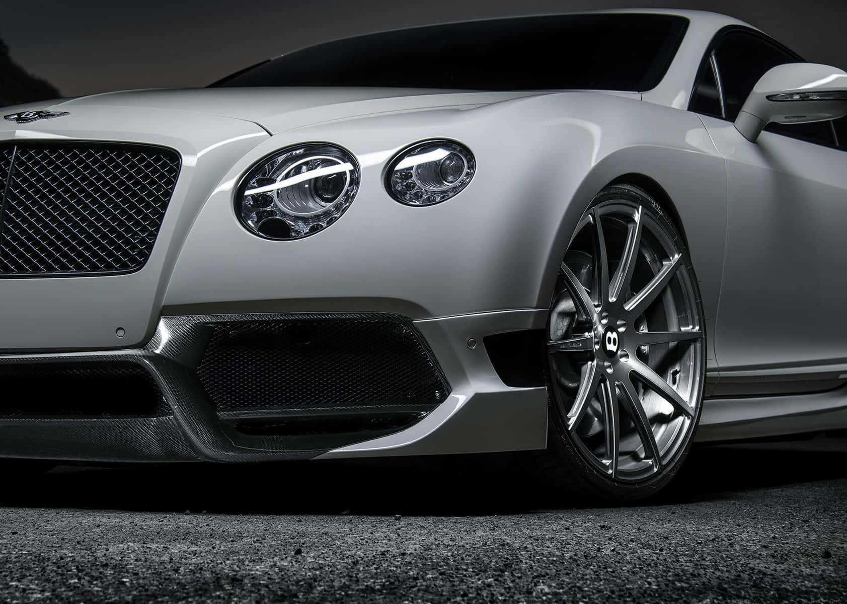 Convertible 桌布 壁紙 — 一輛時尚的銀色賓利 Continental GT，帶有碳纖維飾邊和發光車頭燈，在戲劇性燈光下停在瀝青路面上。