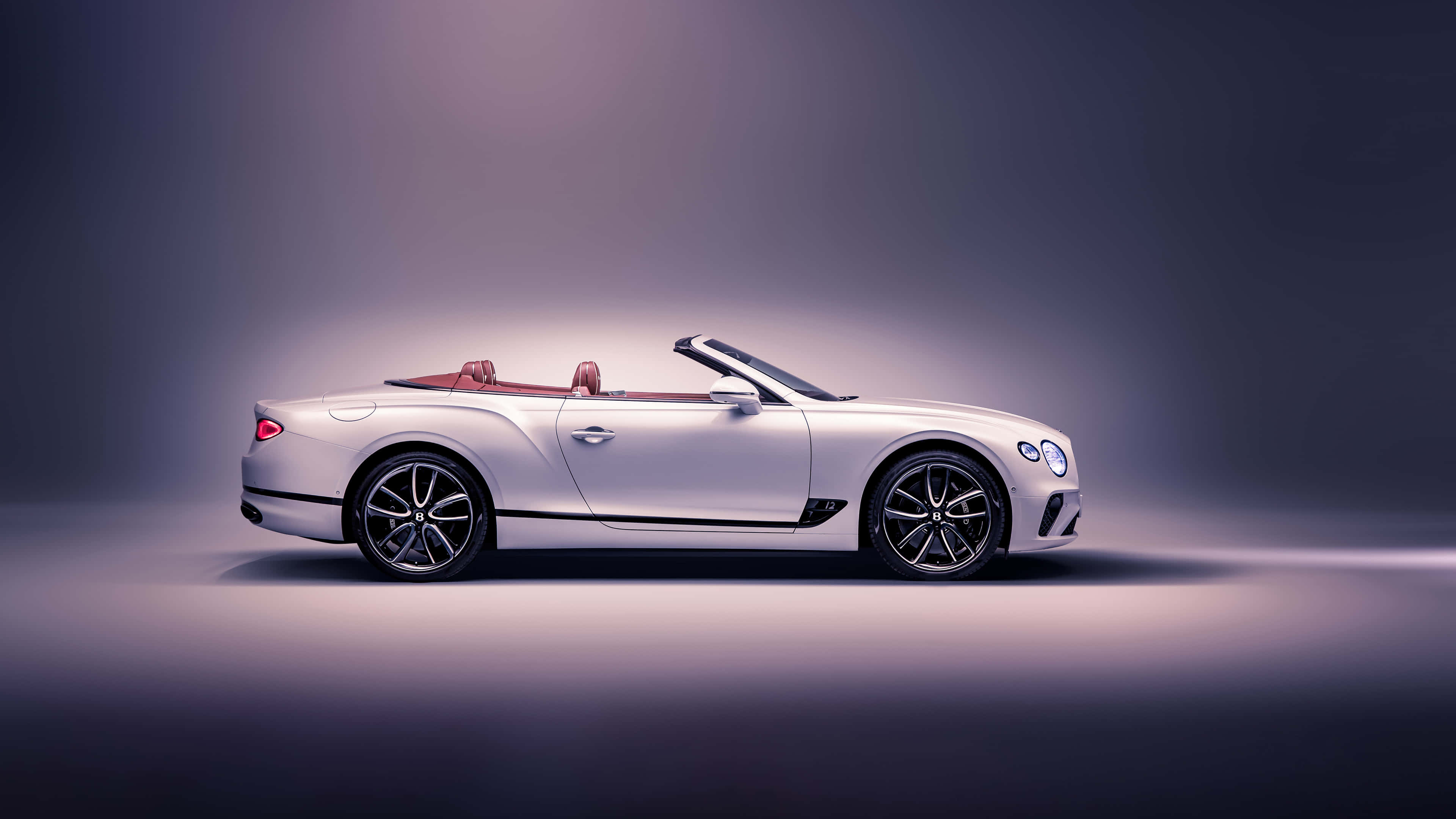 Bentley Continental Gt Convertible 桌布 壁紙 — 一輛時尚的銀色賓利敞篷車配紅色皮革座椅，在柔和紫色燈光的攝影棚中展示。