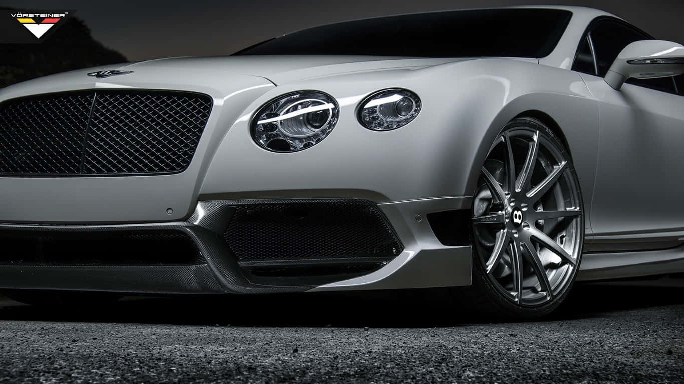1366x768 Bentley 桌布 壁紙 — 一輛時尚的銀色賓利跑車，配備定制輪圈和碳纖維飾件，在戲劇性燈光下停在瀝青路面上。