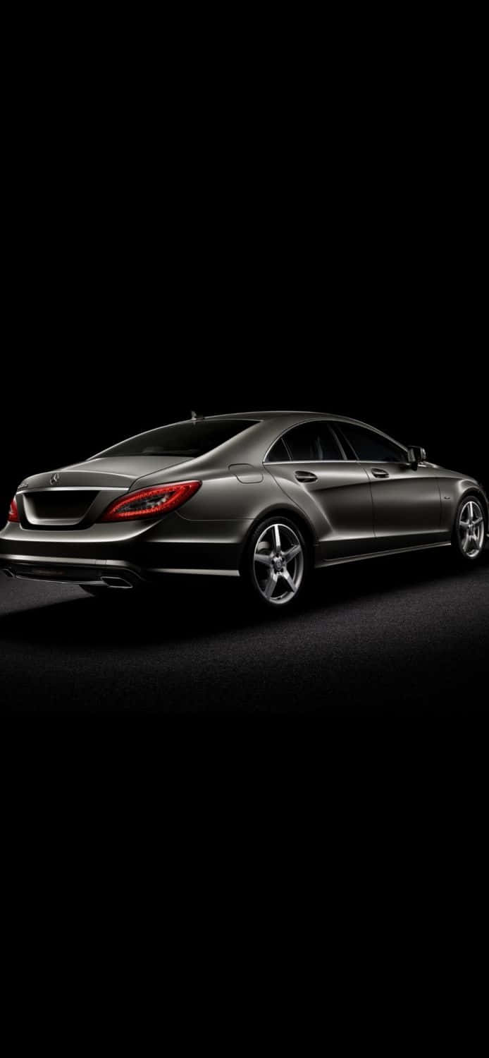 iPhone X Mercedes 桌布 壁紙 — 一輛時尚的銀色賓士CLS轎跑車在純黑色背景下的攝影棚燈光中閃耀。