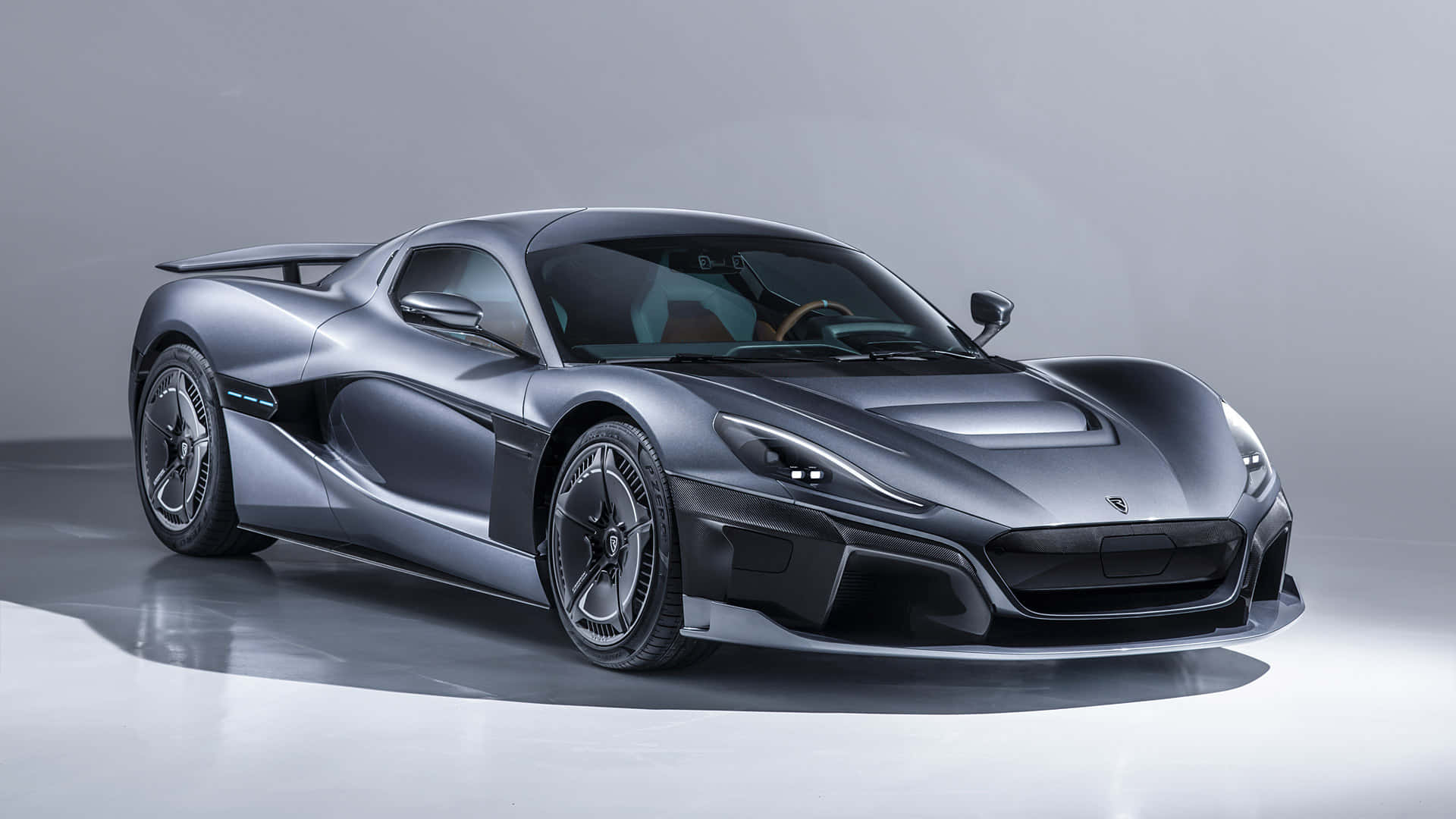 Rimac 桌布 壁紙 — 一輛時尚的銀色超跑，具有空氣動力學曲線和發光頭燈，矗立在簡約的攝影棚地板上。