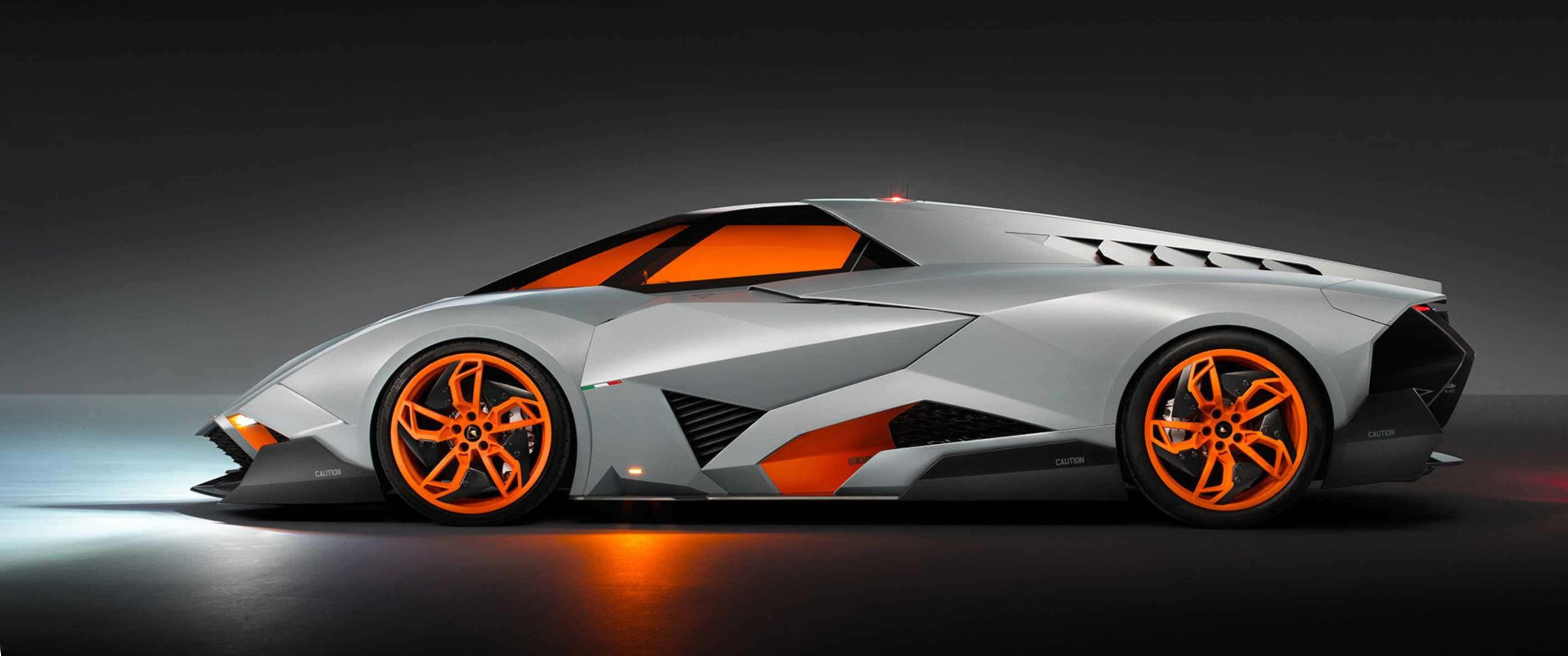 3440x1440p Lamborghini 桌布 壁紙 — 一輛時尚的銀色跑車，在攝影棚燈光下，充滿活力的橙色車輪和內飾閃閃發光。