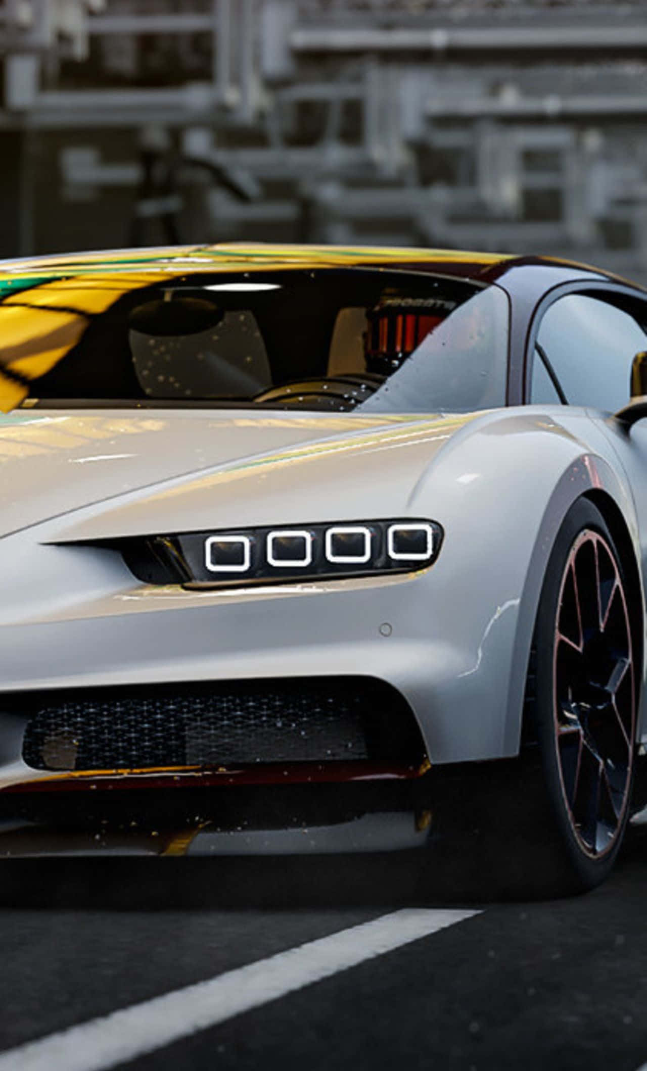 Bugatti Phone 桌布 壁紙 — 一輛時尚的銀色跑車，帶有發光的車頭燈和黃色點綴，停在一個背景模糊的工業道路上。