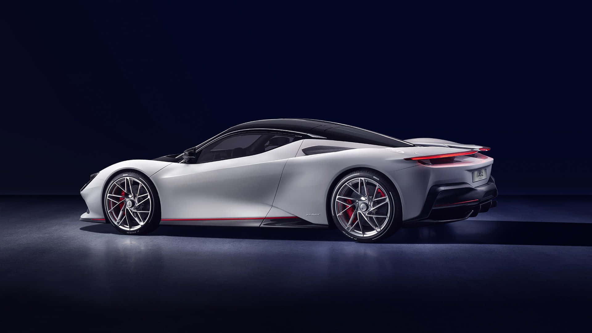 Pininfarina 桌布 壁紙 — 一輛時尚的銀色跑車，帶有紅色點綴和發光的尾燈，在黑暗的攝影棚環境中展示。