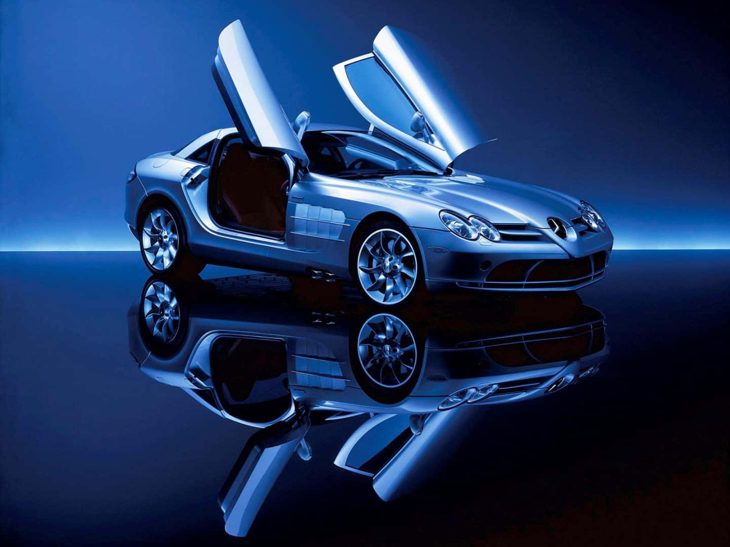 Luxury 桌布 壁紙 — 一輛時尚的銀色跑車，鷗翼門打開，在戲劇性的工作室燈光下完美反射在光亮的藍色表面上。