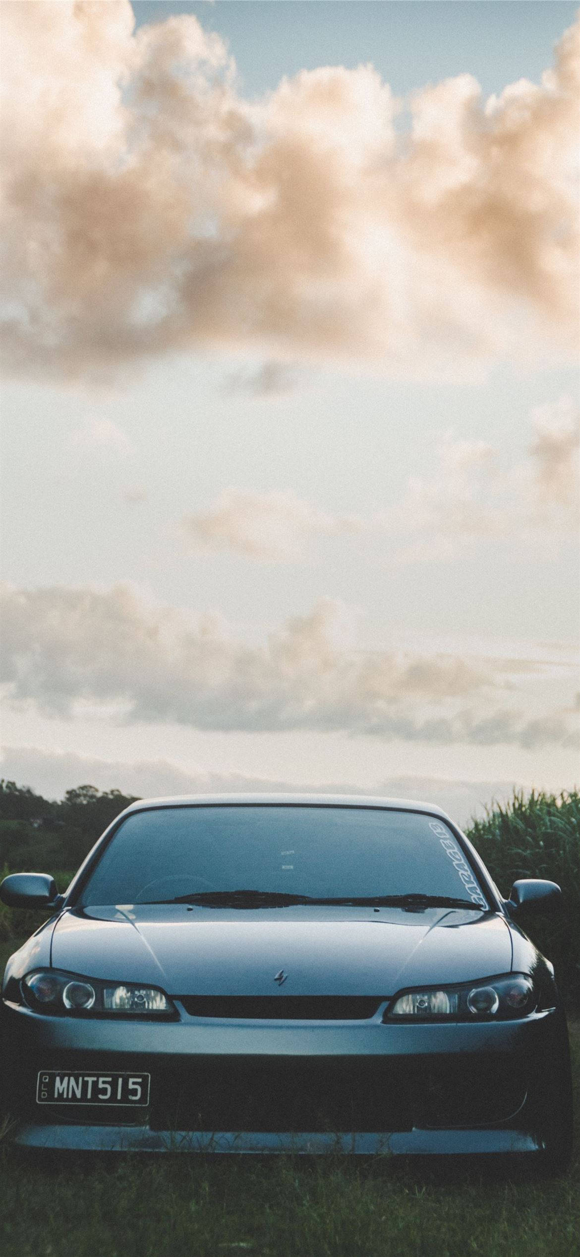 Nissan Silvia S14 桌布 壁紙 — 一輛時尚的銀色跑車停在草地上，背景是黃金時刻戲劇性的多雲天空。