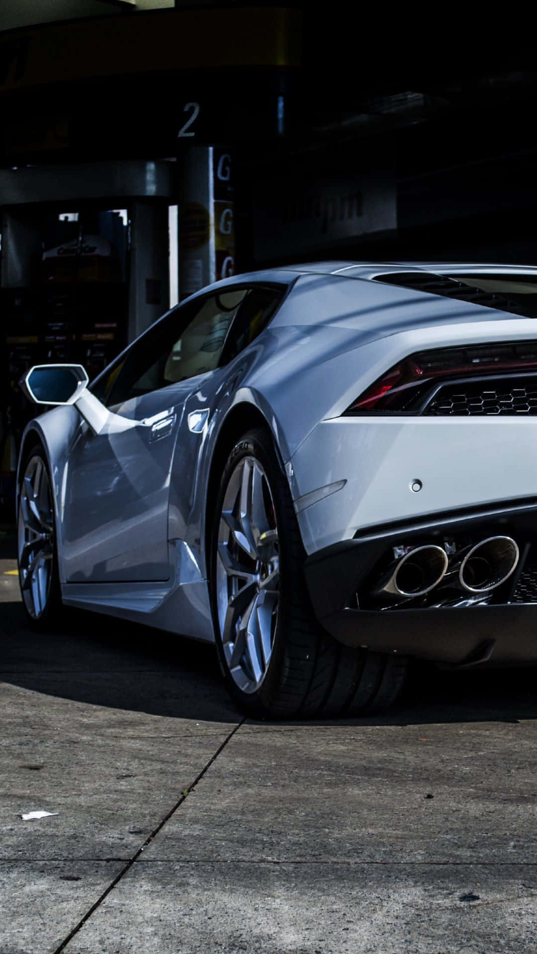 Pixel 3xl Lamborghini 桌布 壁紙 — 一輛時尚的銀色跑車停放在加油站，在強烈的陽光下投射出清晰的陰影。