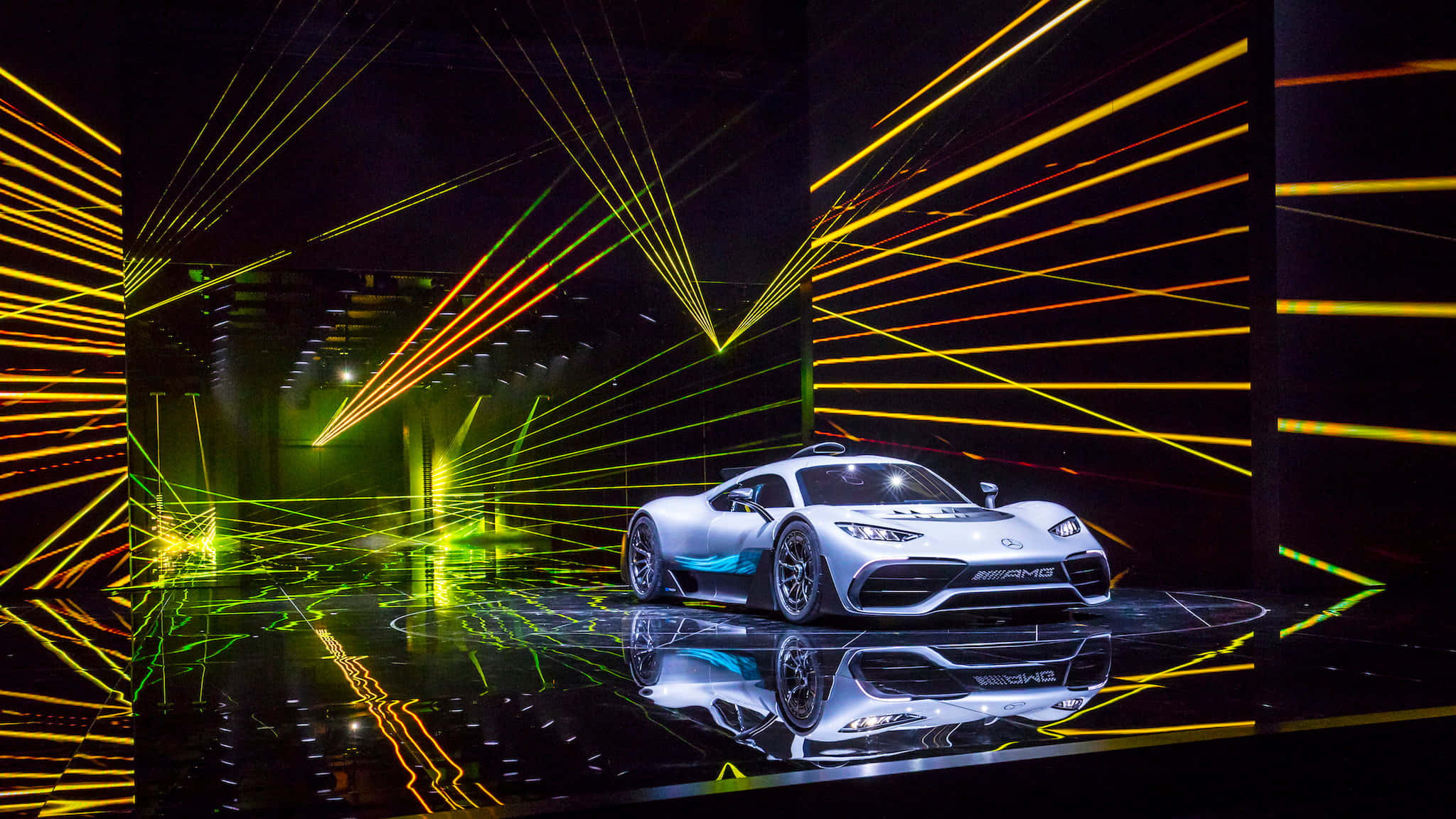 Mercedes 桌布 壁紙 — 一輛時尚的銀色跑車在反射舞台上，在充滿活力的黃色和綠色雷射燈下閃閃發光。