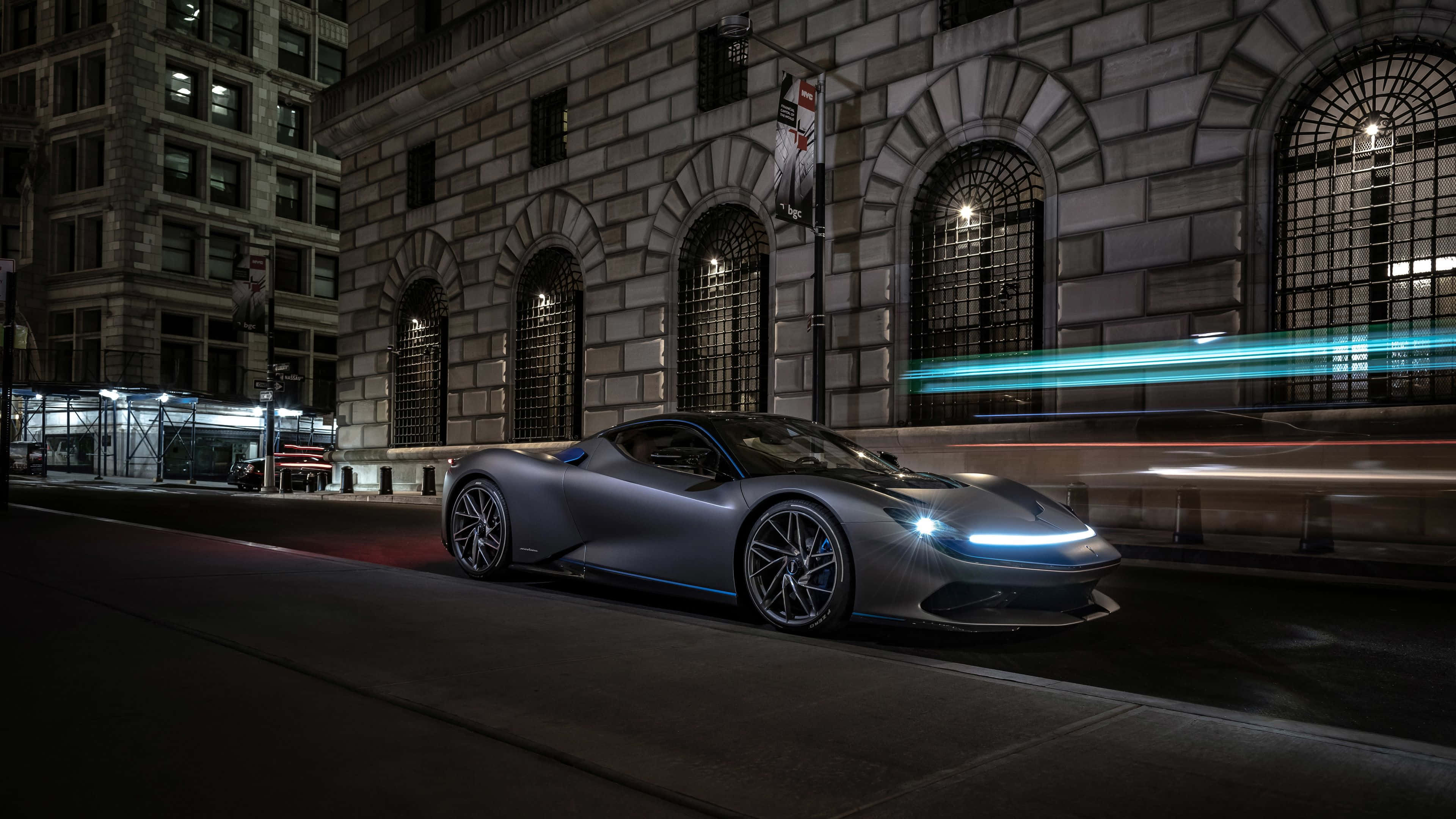 Pininfarina 桌布 壁紙 — 一輛時尚的銀色跑車在夜晚穿梭於霓虹燈照亮嘅城市街道，伴隨著來往車輛的動態模糊痕跡。