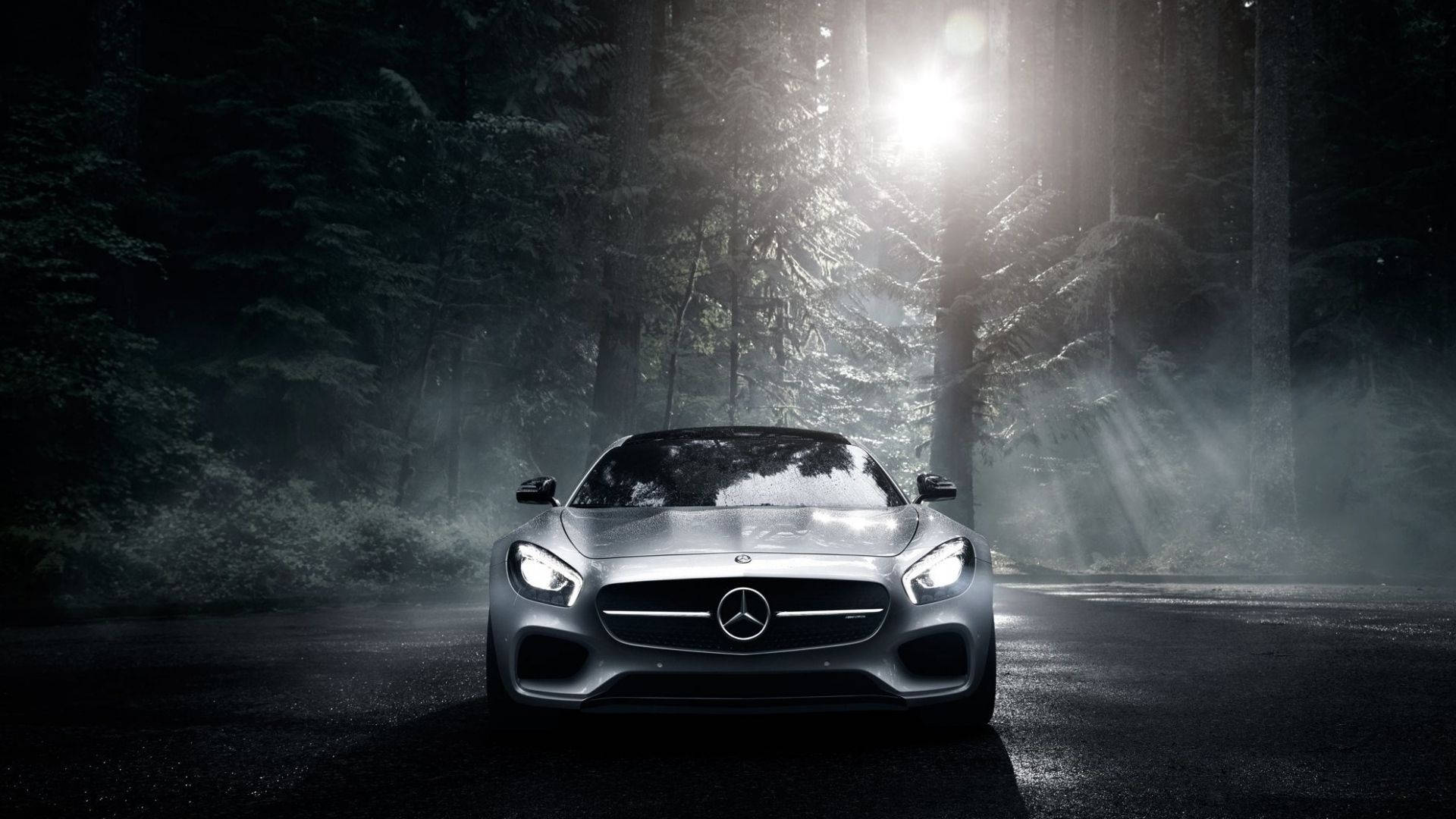 Mercedes 桌布 壁紙 — 一輛時尚的銀色跑車在夜間戲劇性的森林光束下發光，薄霧在其車頭燈周圍旋轉。