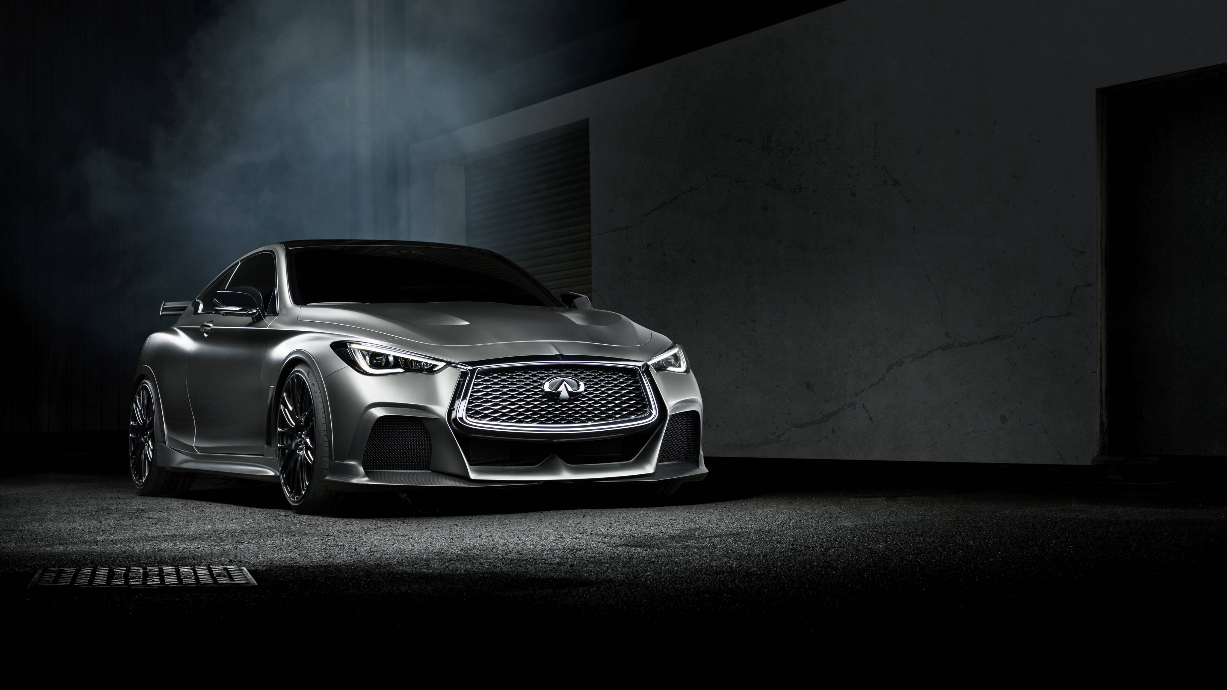 Infiniti 桌布 壁紙 — 一輛時尚的銀色跑車在煙霧瀰漫的黑暗車庫中，在戲劇性的聚光燈下閃耀，車庫有混凝土牆壁。