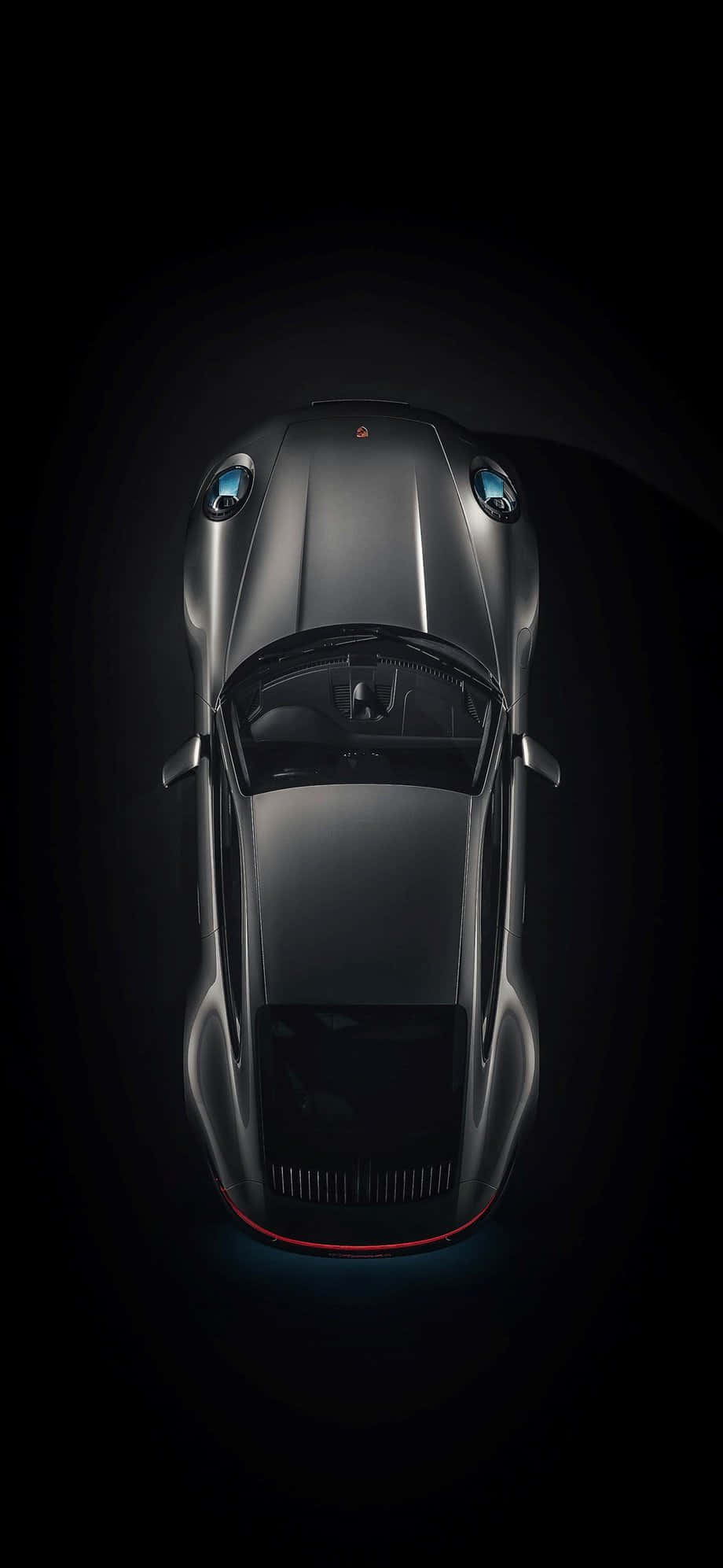 Porsche iPhone 桌布 壁紙 — 一輛時尚的銀色跑車從上方俯瞰，背景為黑色，帶有發光的藍色車頭燈和紅色底盤燈。