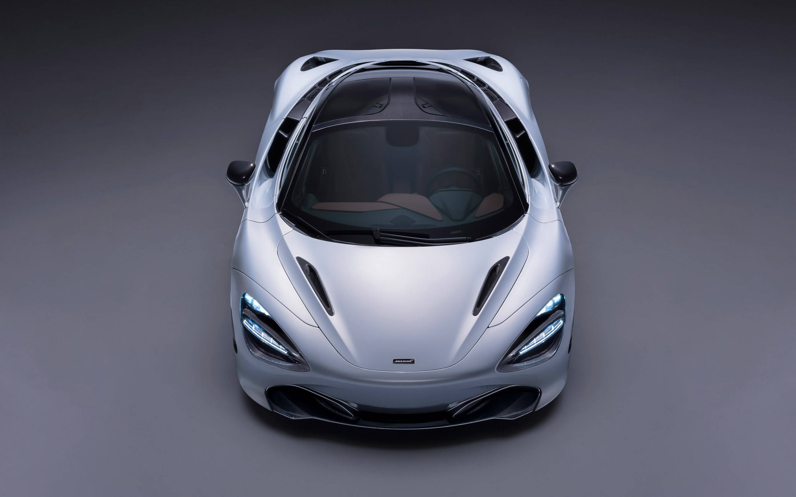 mclaren 720s 4K 桌布 壁紙 — 一輛時尚的銀色跑車從上方觀看，車頭燈發光，背景為深灰色工作室。