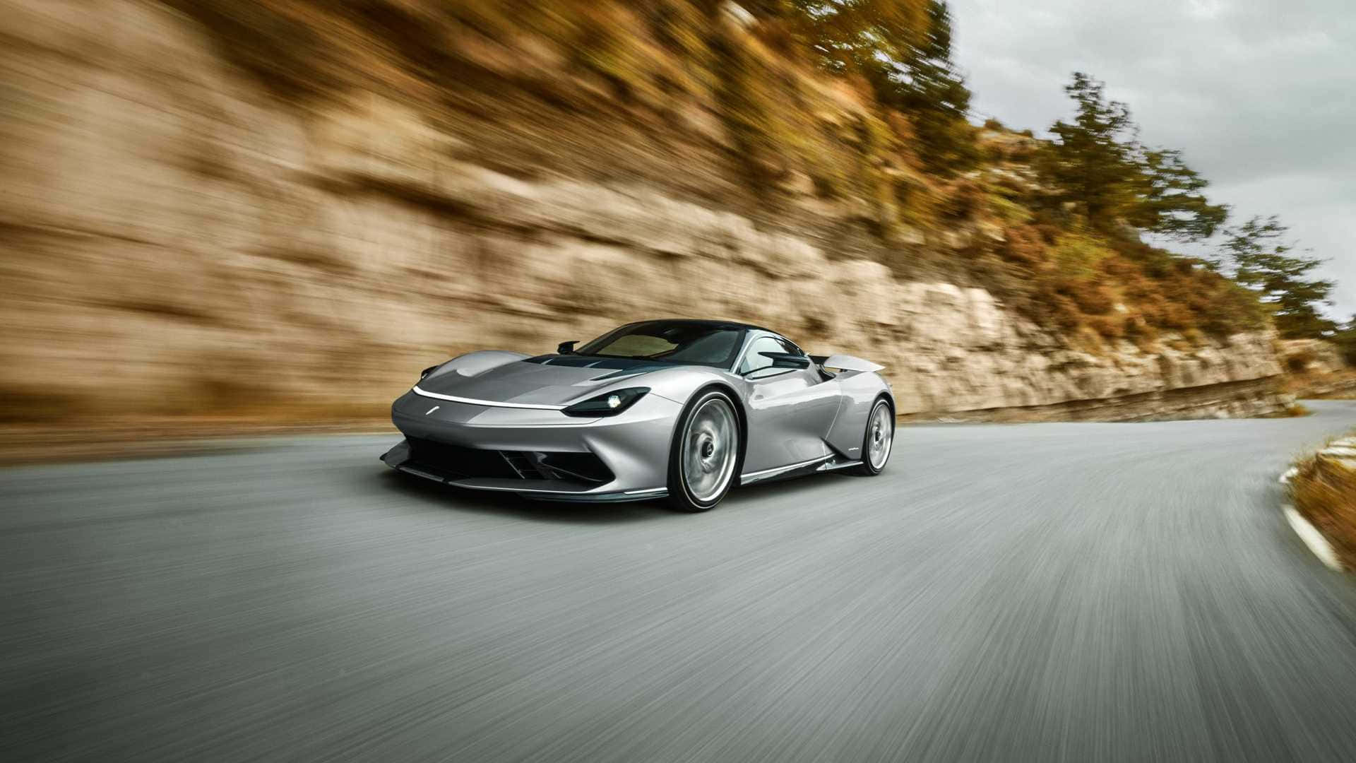 Pininfarina 桌布 壁紙 — 一輛時尚的銀色跑車沿著蜿蜒的山路疾馳，背景是模糊的岩石懸崖和秋樹。