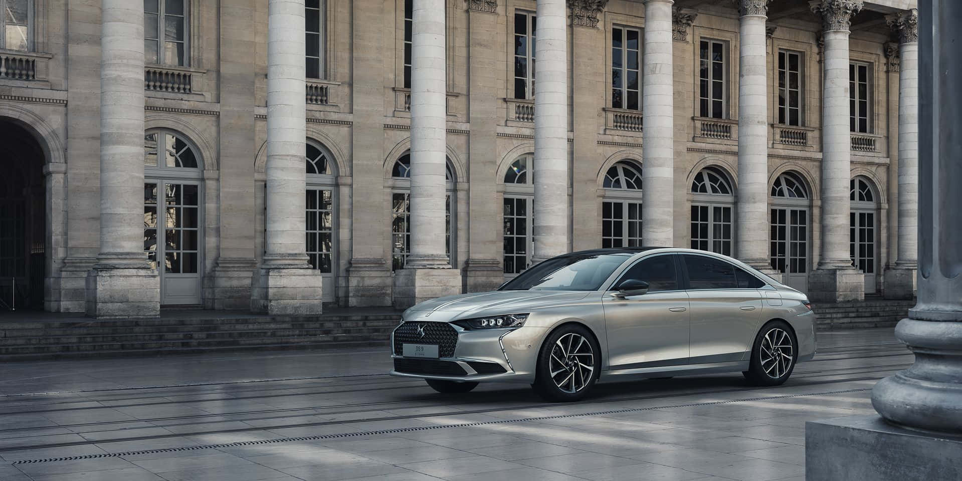 Ds Automobiles 桌布 壁紙 — 一輛時尚的銀色轎車停在一棟宏偉的新古典主義建築前，建築有高大的柱子和拱形窗戶。