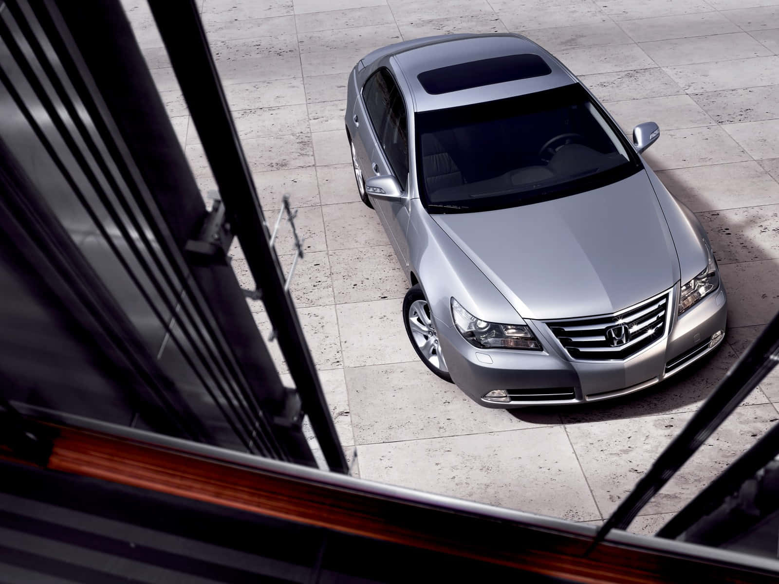 Honda Legend 桌布 壁紙 — 一輛時尚的銀色轎車停在石磚上，從上方透過現代玻璃框架觀看。