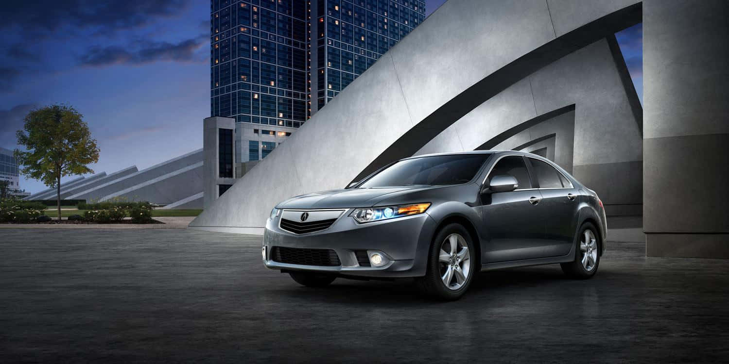 Acura Tsx 桌布 壁紙 — 一輛時尚的銀色轎車停放在現代混凝土拱門下，背後有玻璃摩天大樓在黃昏中發光。