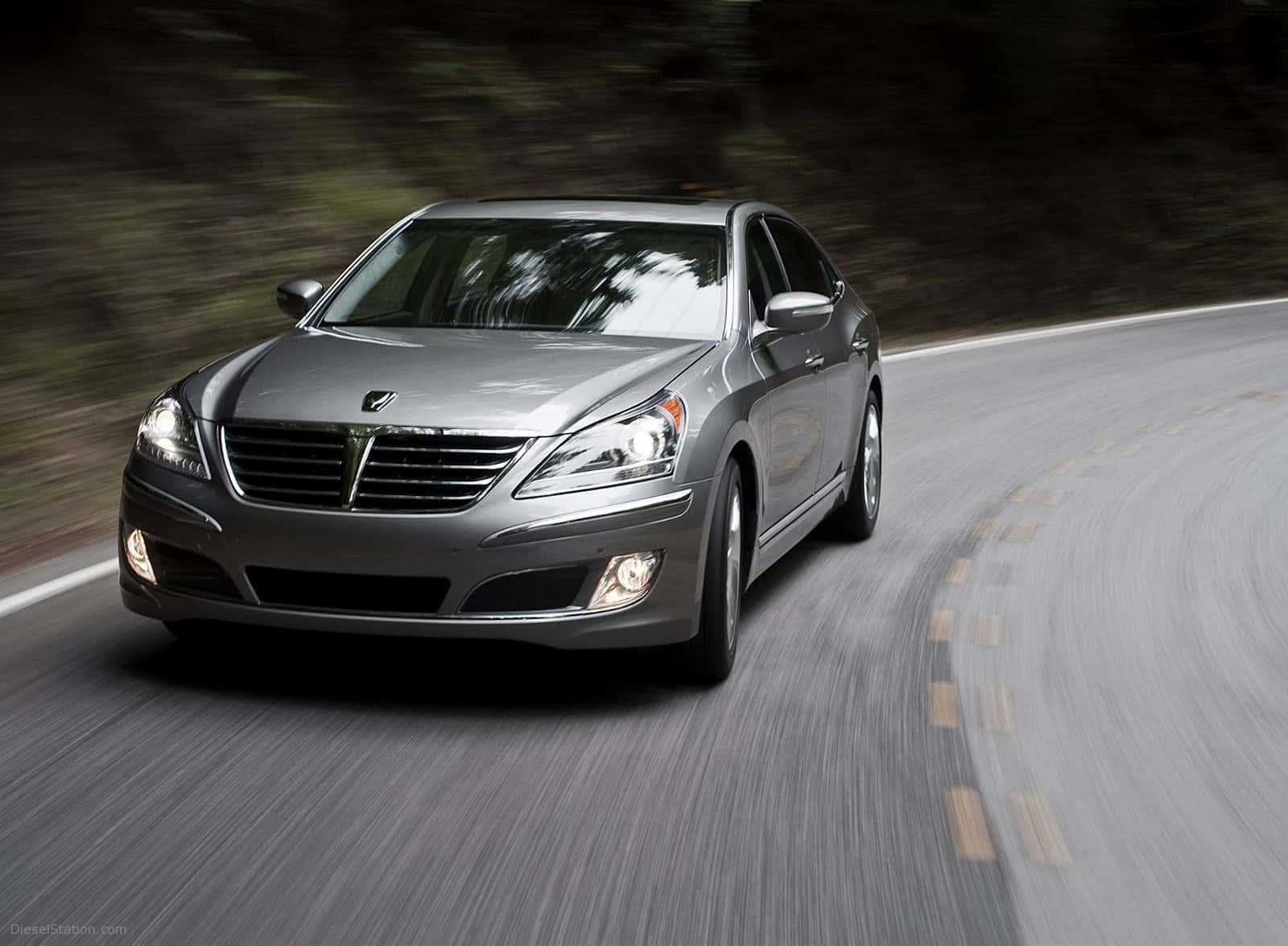 Hyundai Equus 桌布 壁紙 — 一輛時尚的銀色轎車在蜿蜒的道路上疾馳，模糊的森林背景傳達出動感與力量。