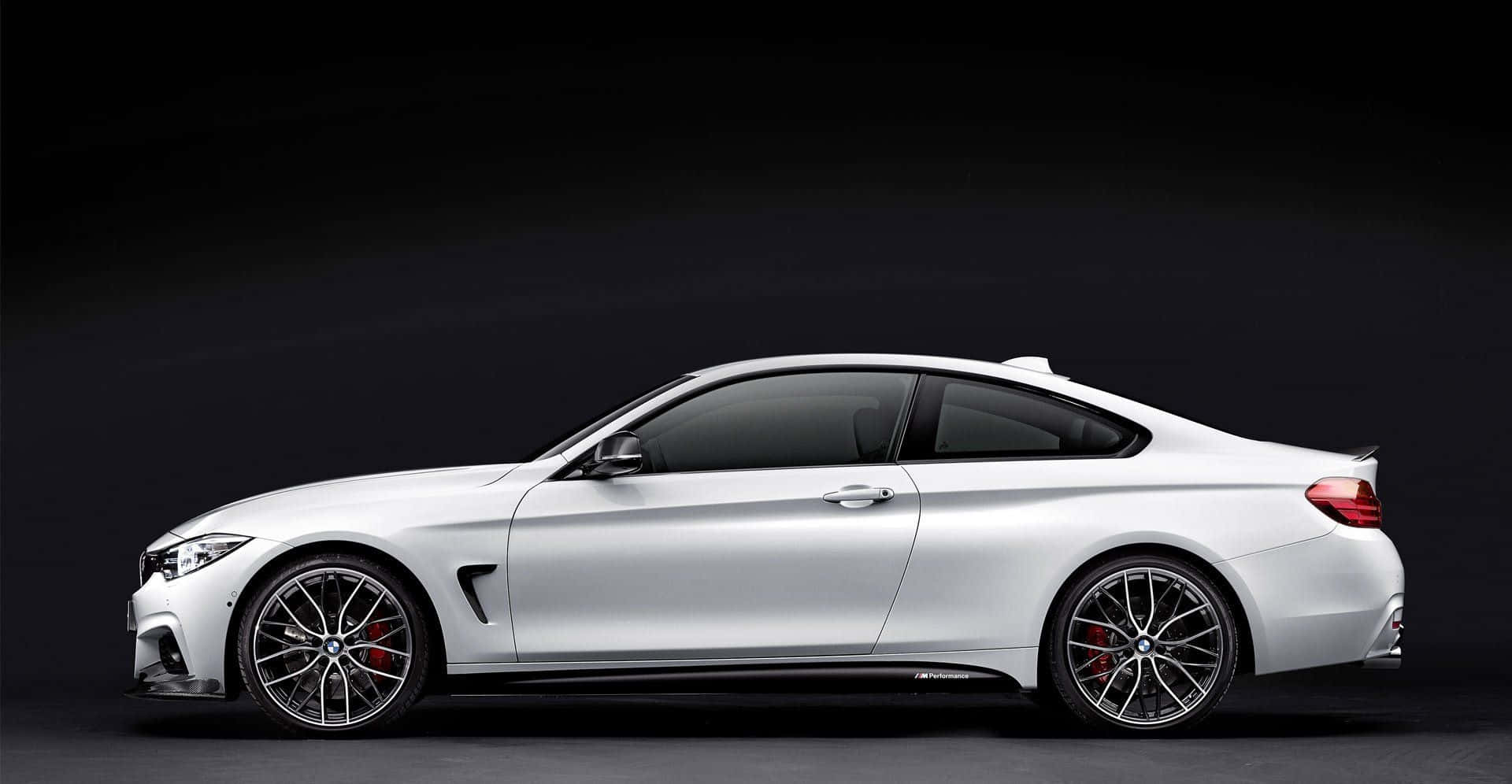 Bmw 4 Series 桌布 壁紙 — 一輛時尚的銀色運動轎跑車，配備黑色輪圈和紅色制動卡鉗，在深色工作室背景下側面展示。