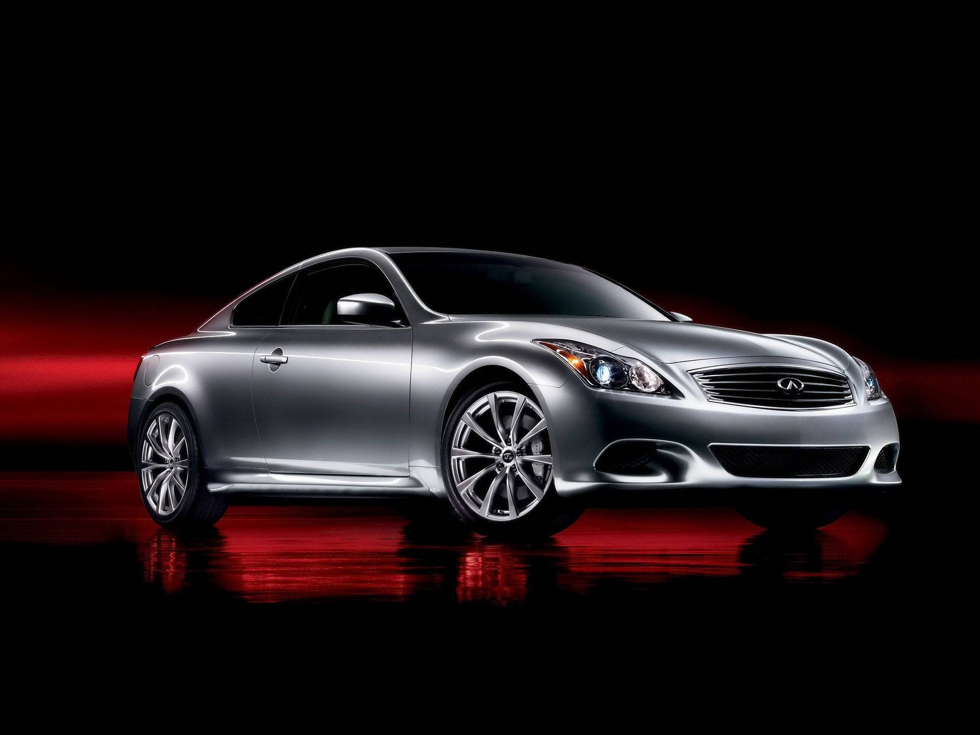 Infiniti 桌布 壁紙 — 一輛時尚的銀色運動轎跑車在黑色背景和反光地板上，在戲劇性的紅色燈光下閃閃發光。